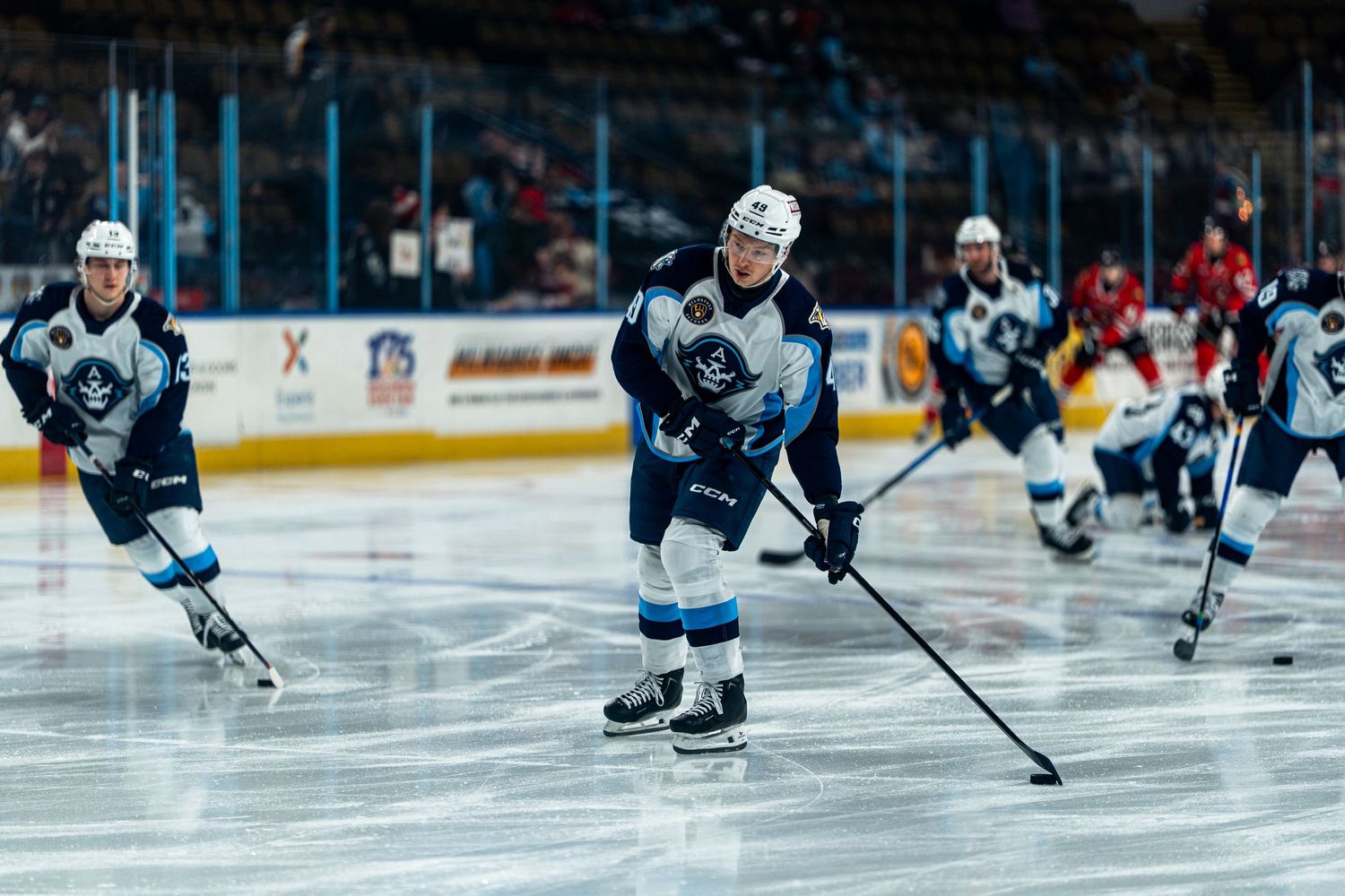 Hockey players in white and dark uniforms chase after the puck during an intense game on the ice.
