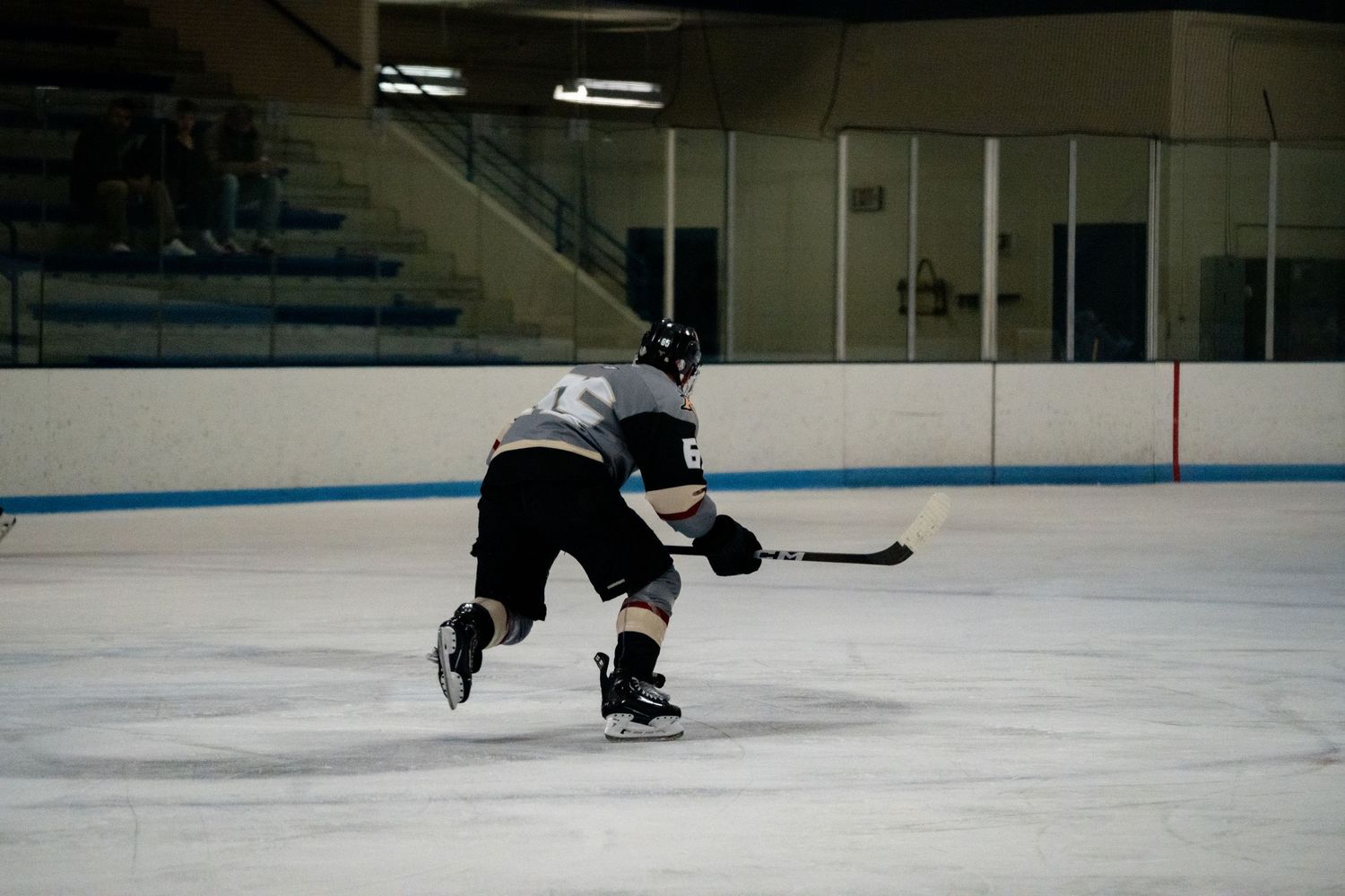 Players maneuver on the ice during a hockey game in an indoor arena.