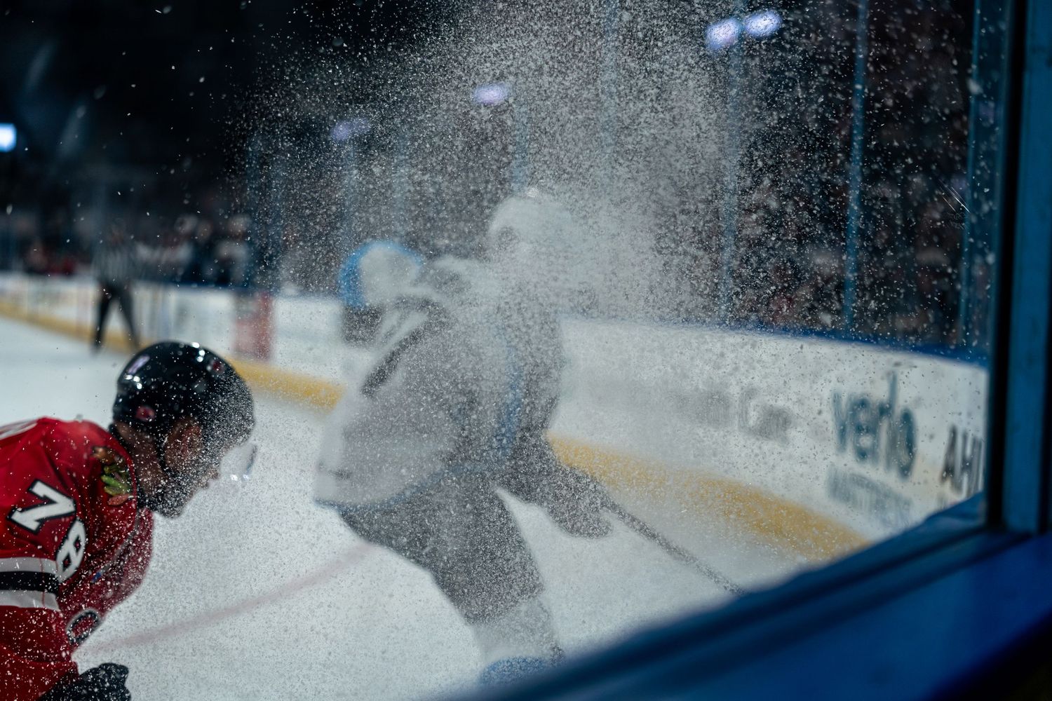 Ice sprays up during a fast-paced hockey game as players maneuver on the rink.