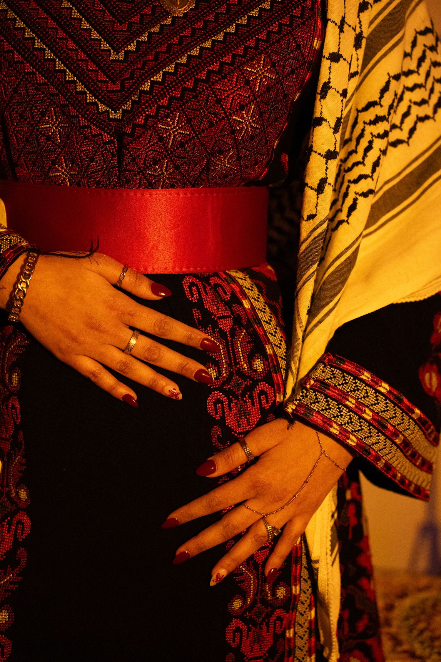 Close-up details of intricate embroidery patterns on traditional clothing in rich red and gold colors.
