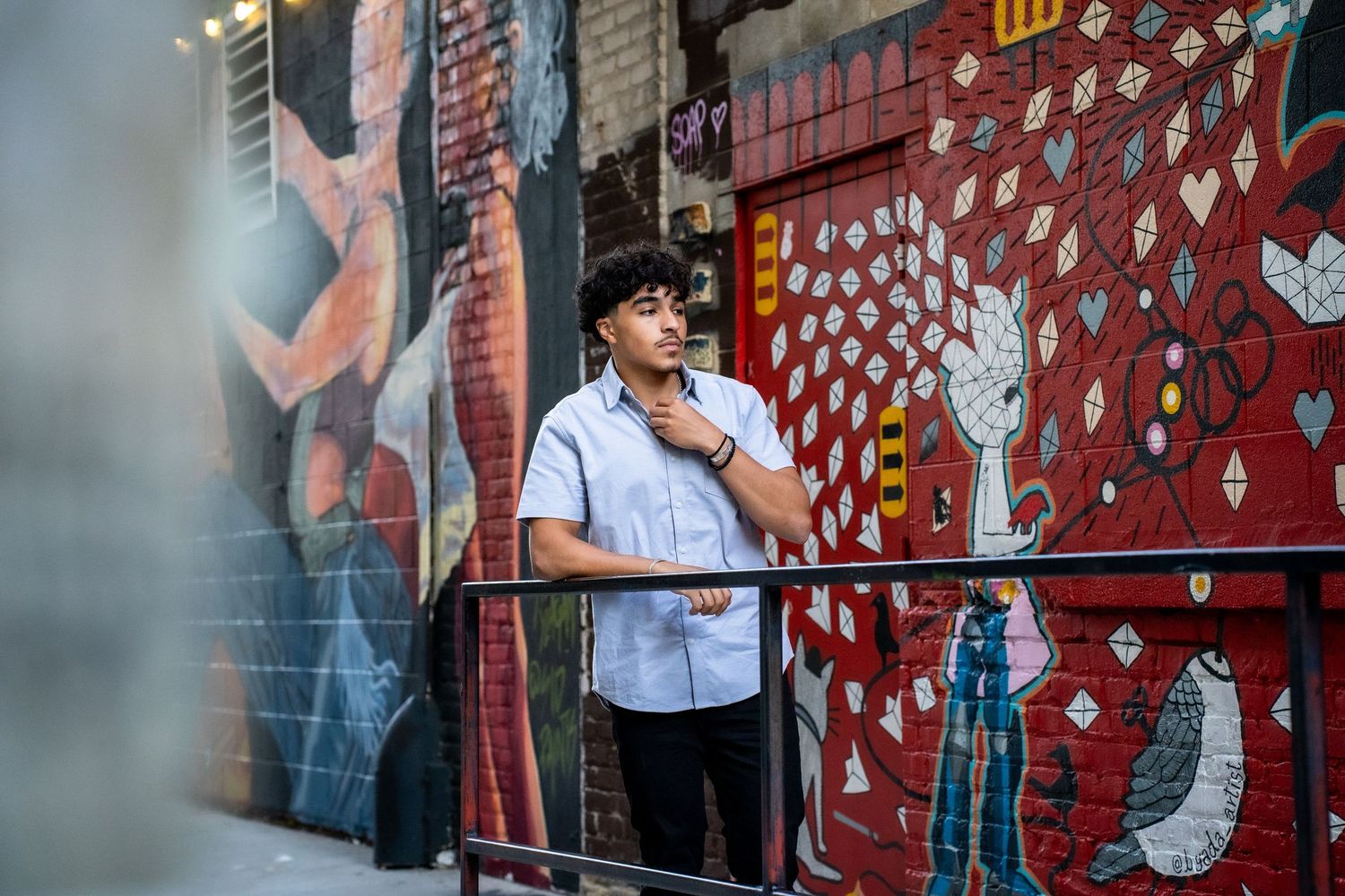 Urban scene with red brick wall covered in artistic graffiti.