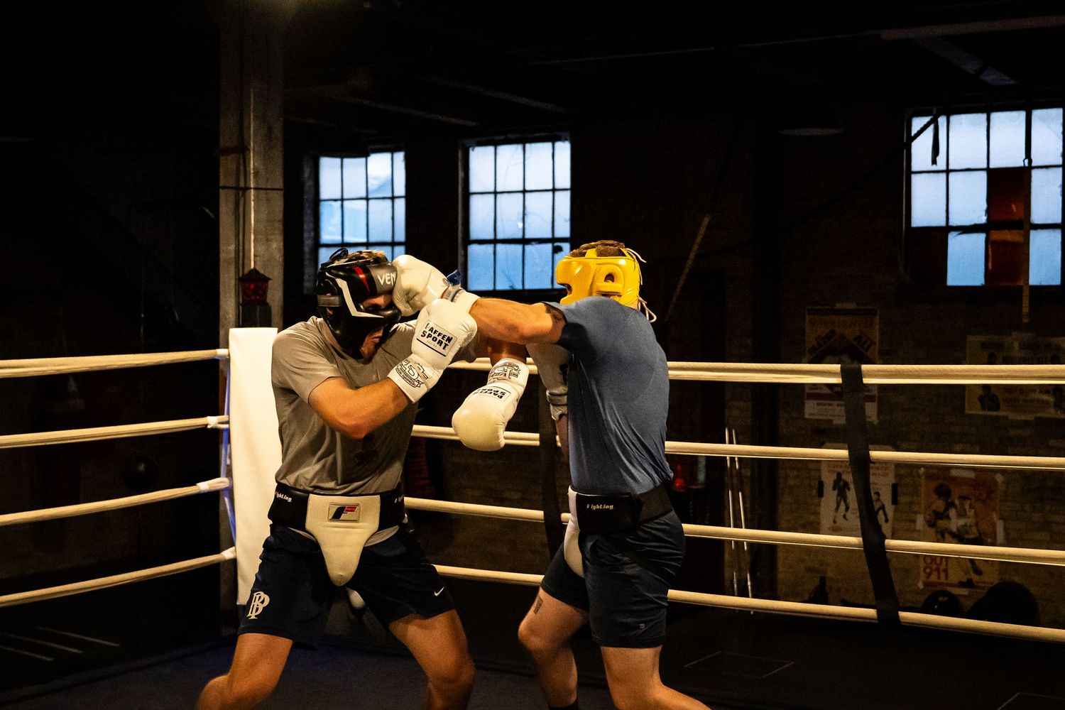 Sparring partners practice boxing techniques in a classic boxing ring setting.