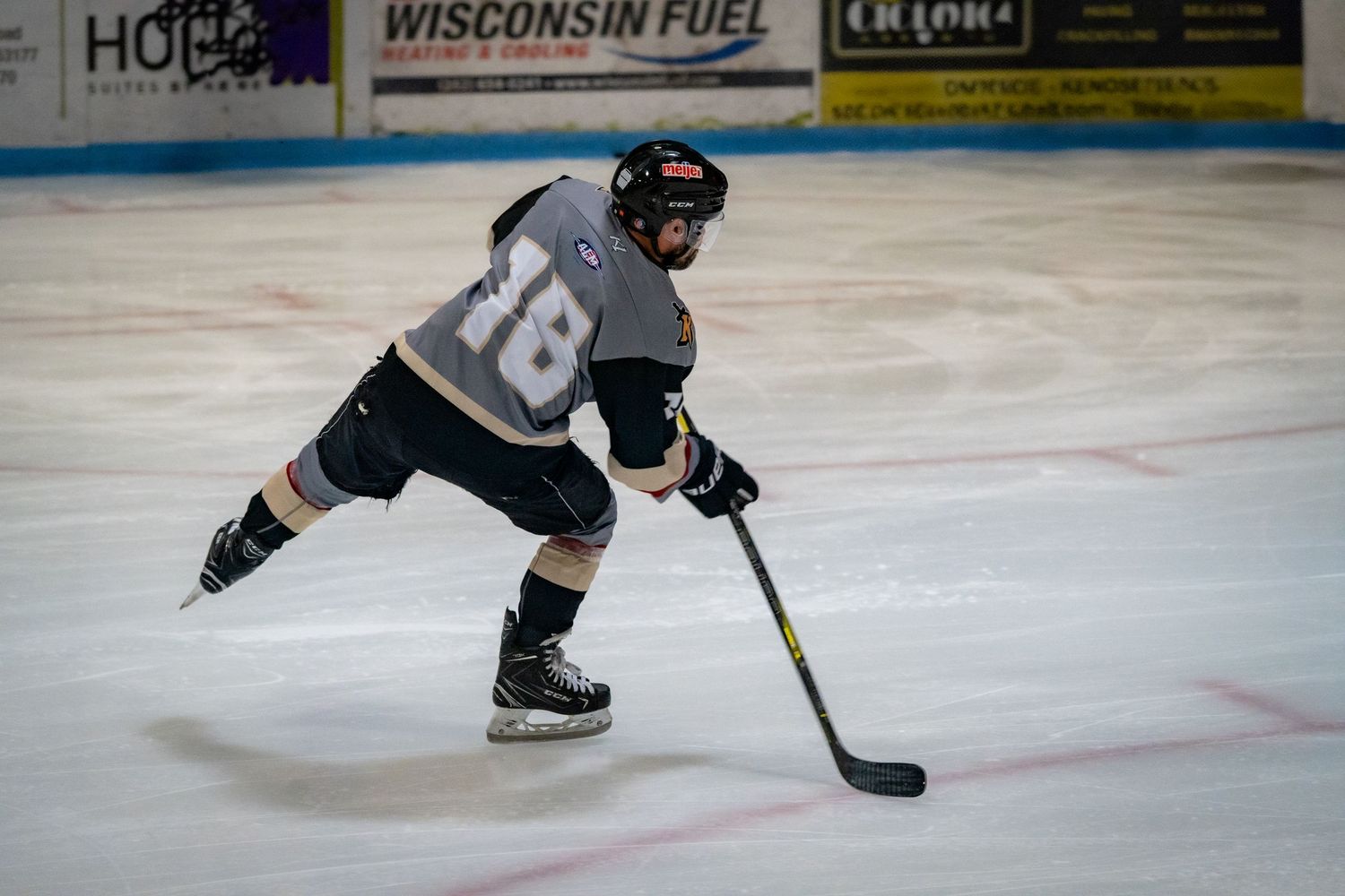 Ice hockey player demonstrates skating technique while practicing on indoor rink.