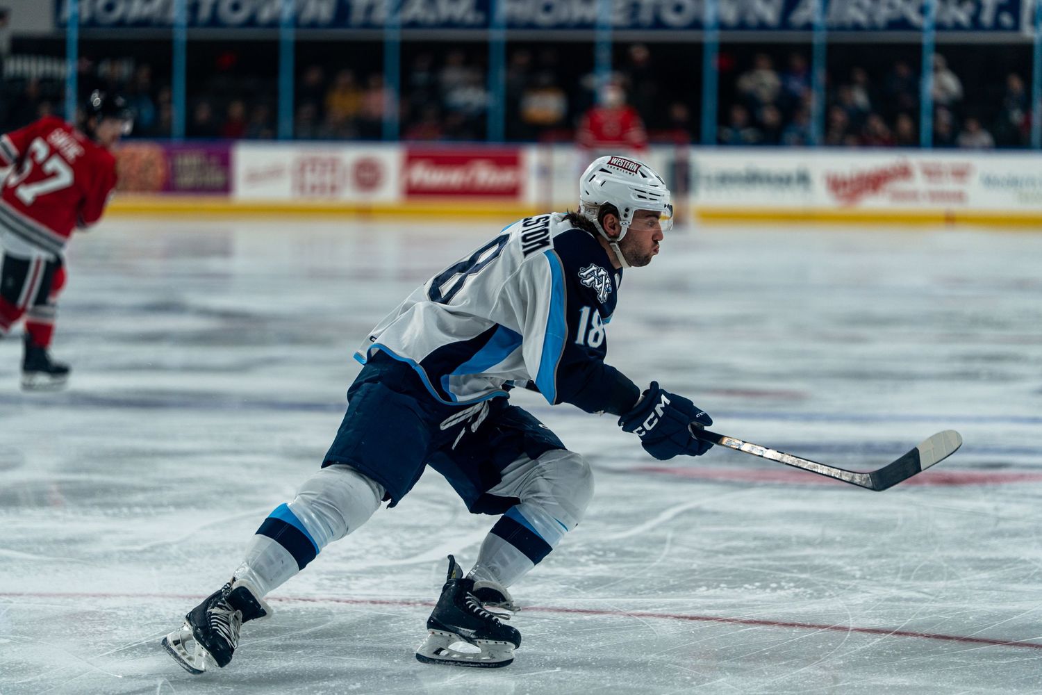 Hockey players chase after the puck during an intense game on the ice.
