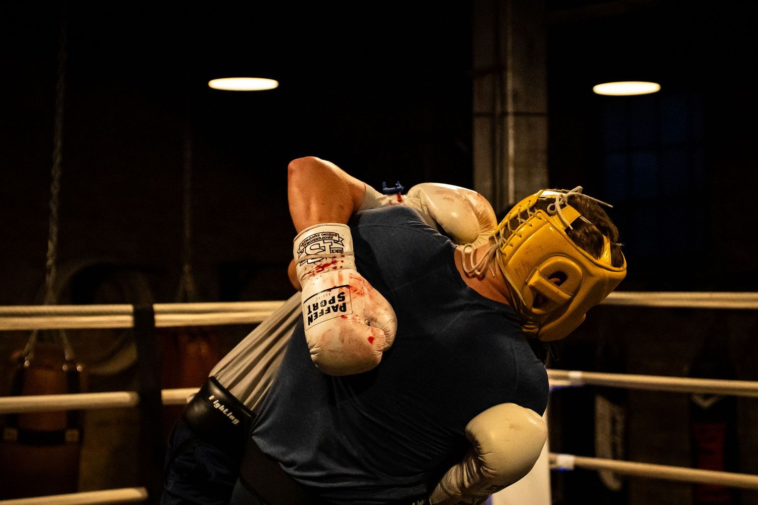 Boxers in protective gear practicing combinations near boxing ring corner.