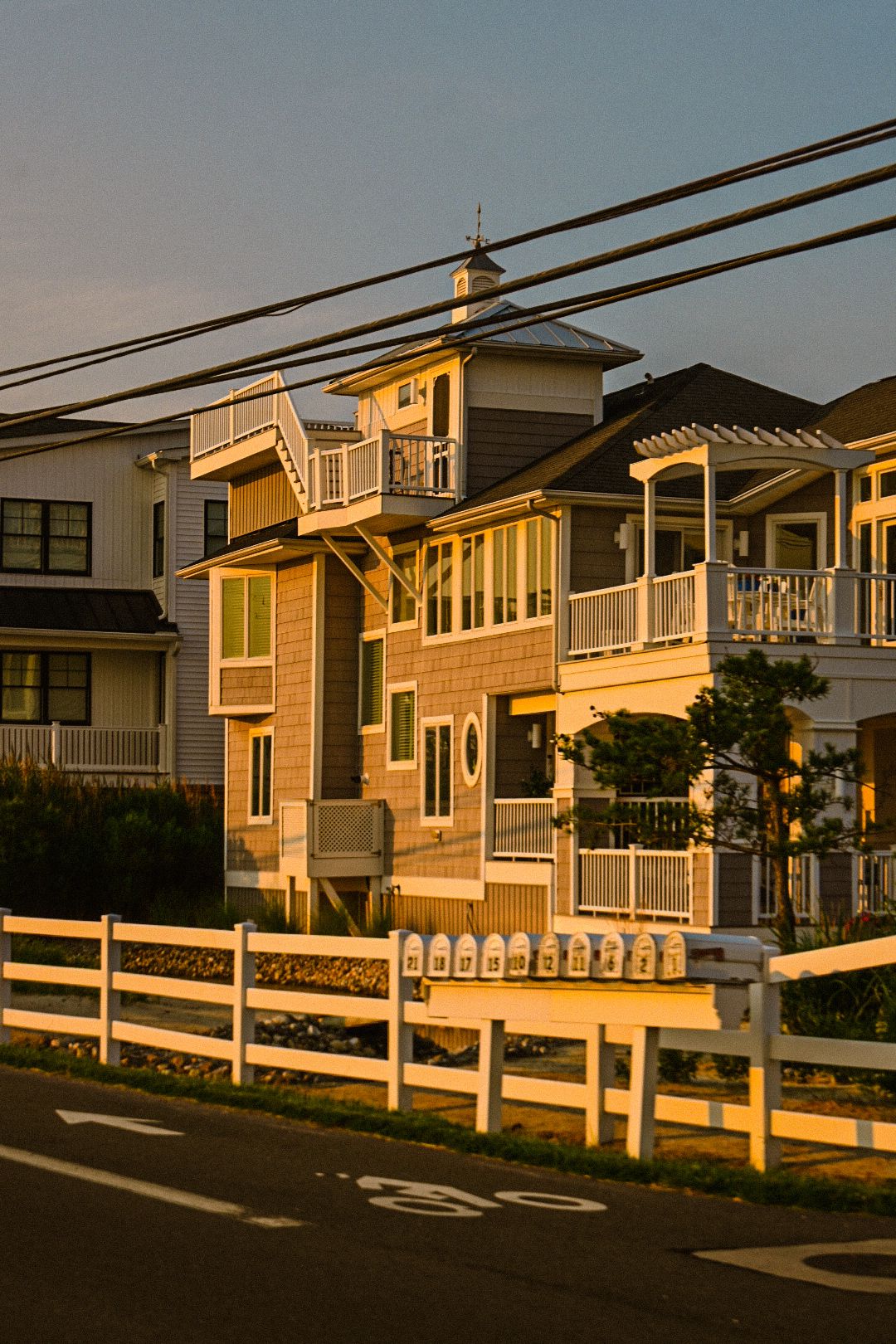 Coastal beach houses with white railings and porches at sunset.