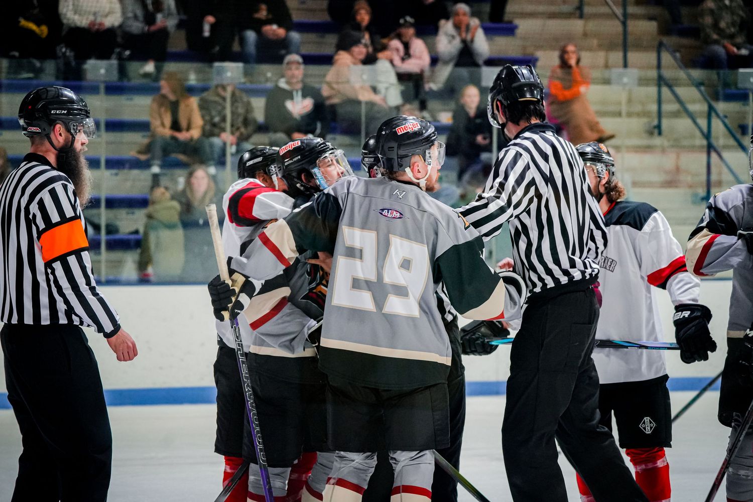 Hockey referees intervene during a tense moment between players on the ice.