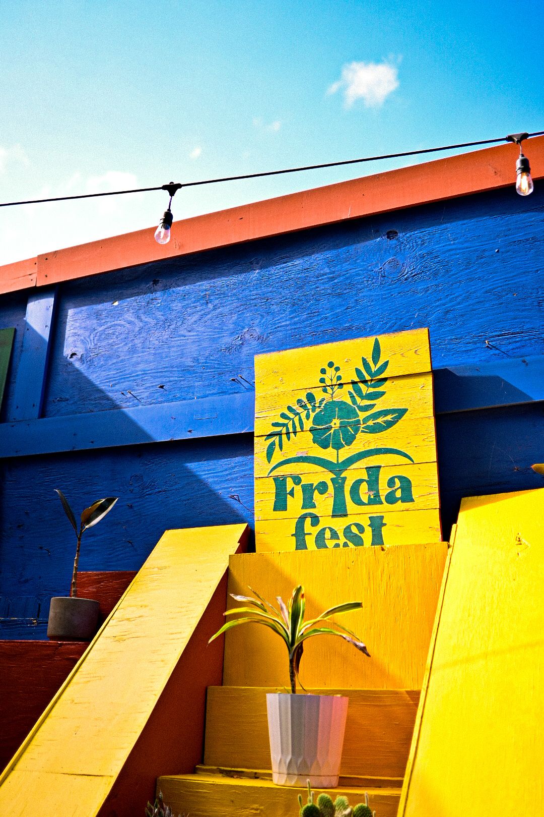 Colorful Frida Fest sign displayed on bright blue wall with yellow accents.