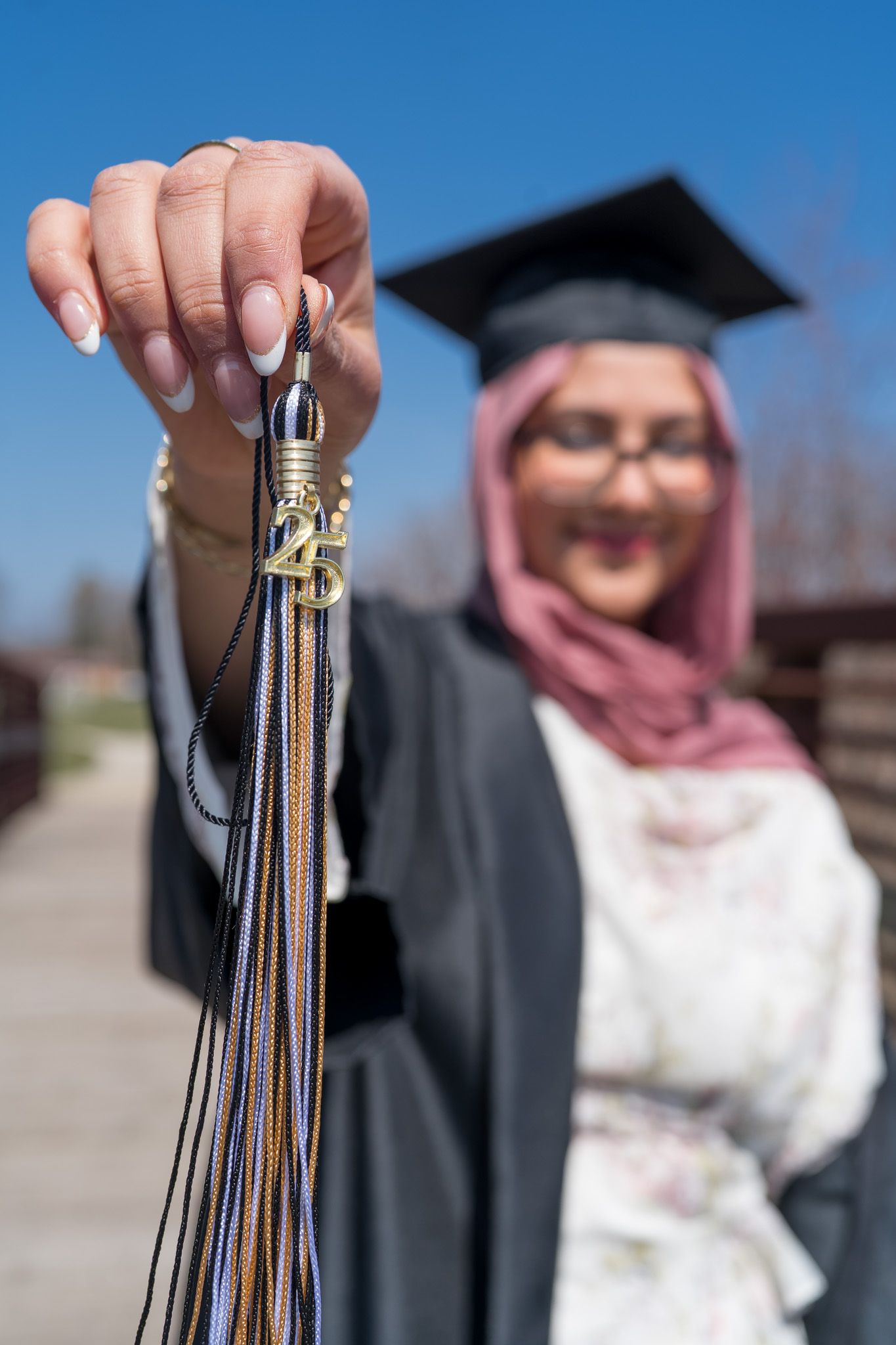 Graduation tassels being held up against a bright blue sky background showing academic achievement.