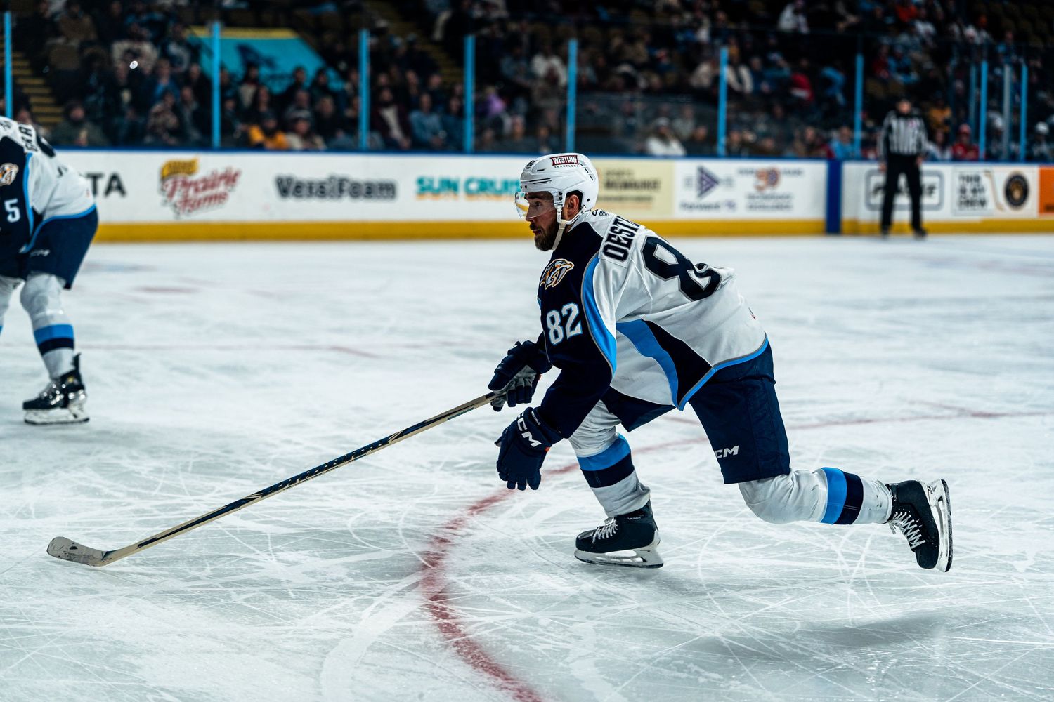 Hockey players skate across the ice during a professional match with arena boards visible.