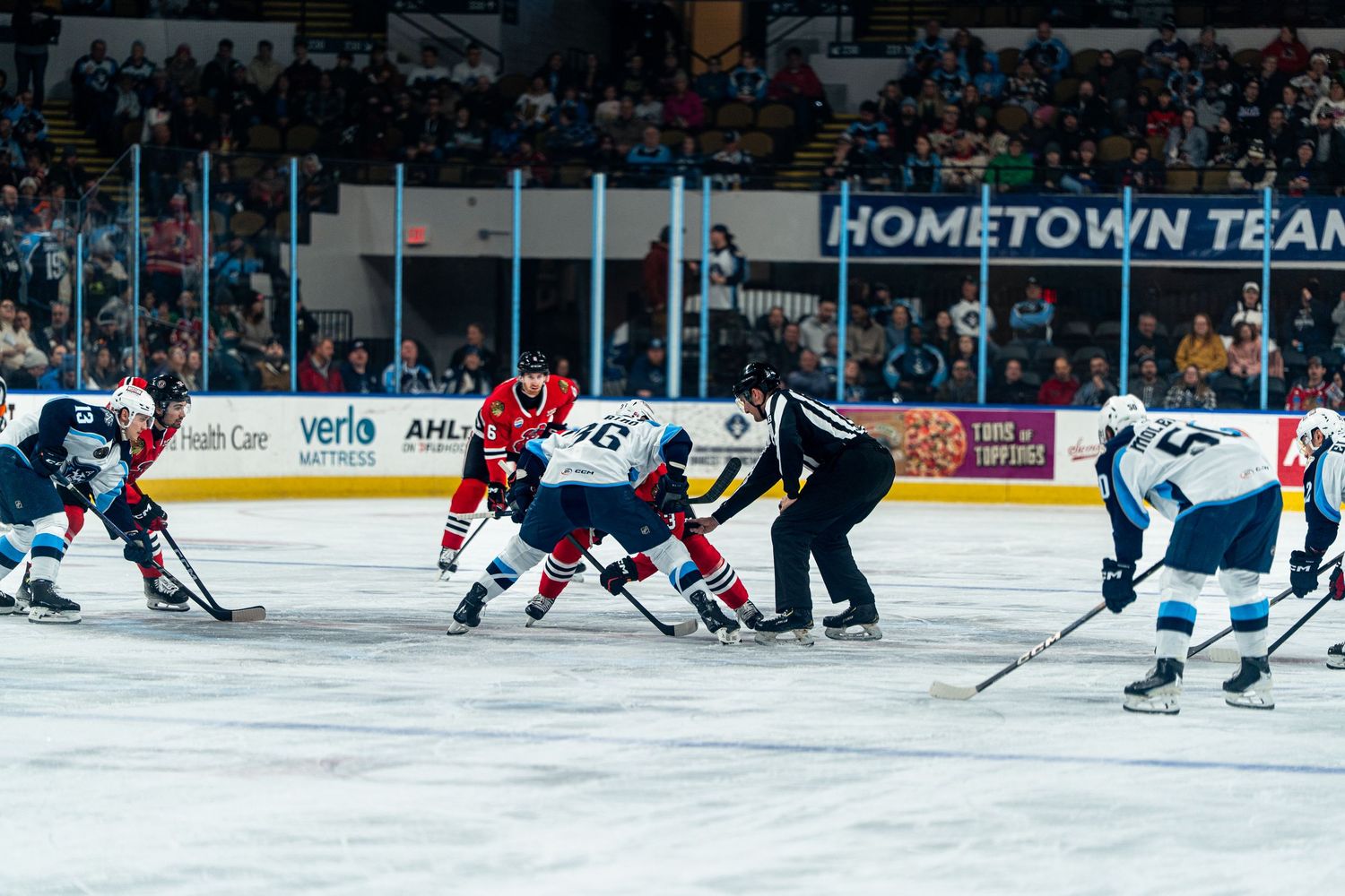 Hockey players compete during a professional match with hometown team banner visible.