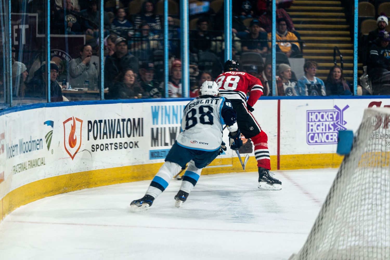 Two hockey teams face off near the goal during an AHL game with arena advertising visible.