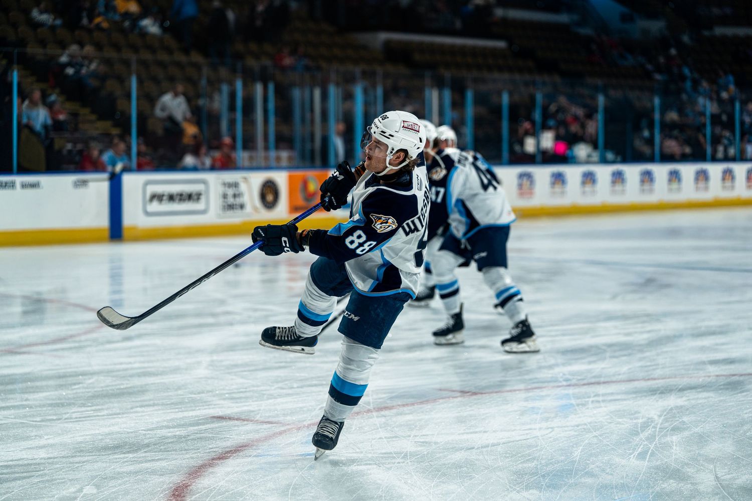 Hockey players chase after the puck during an intense game on the ice rink.