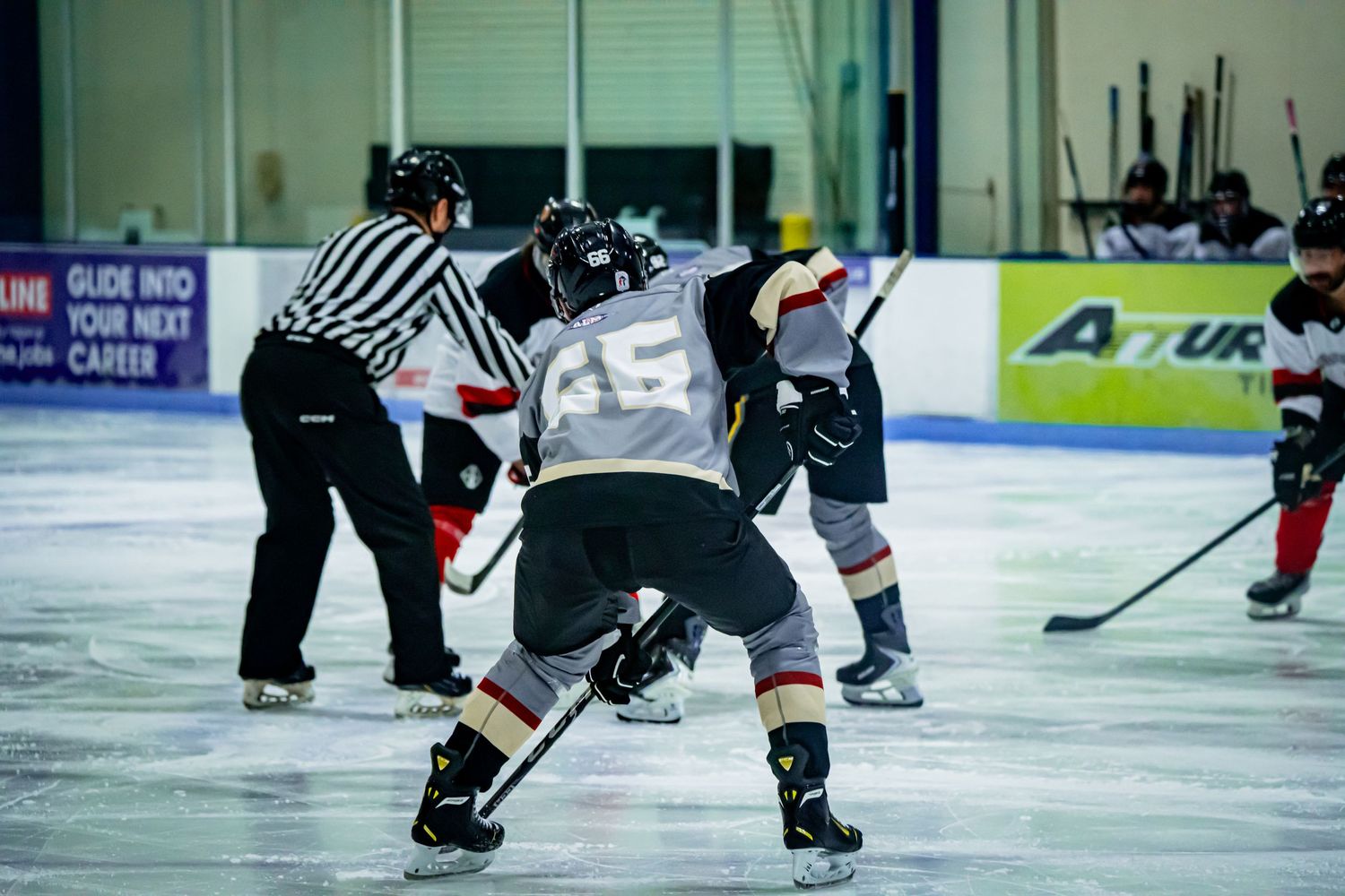 Hockey players in black uniforms compete for puck possession during game.