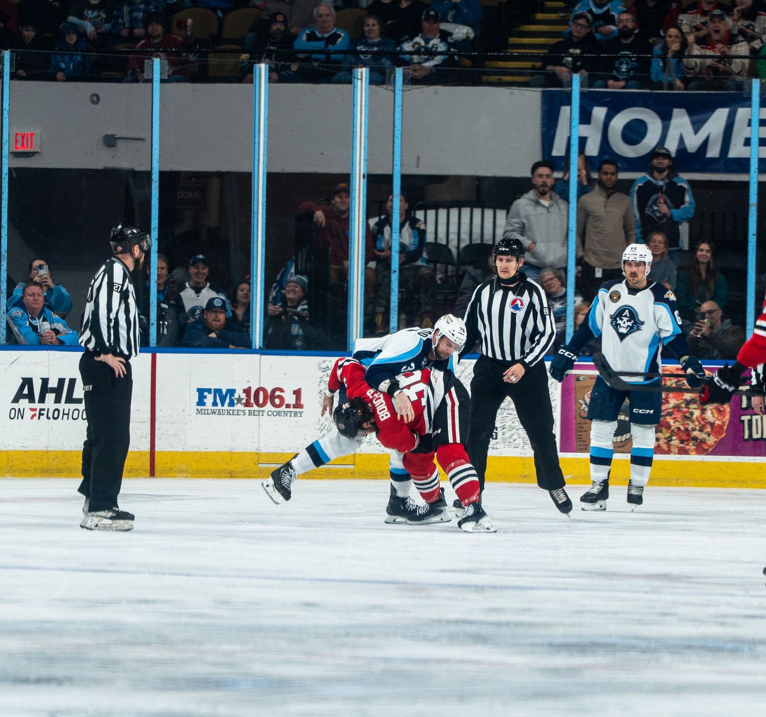 Wide view of a hockey arena during a professional match with officials on ice.