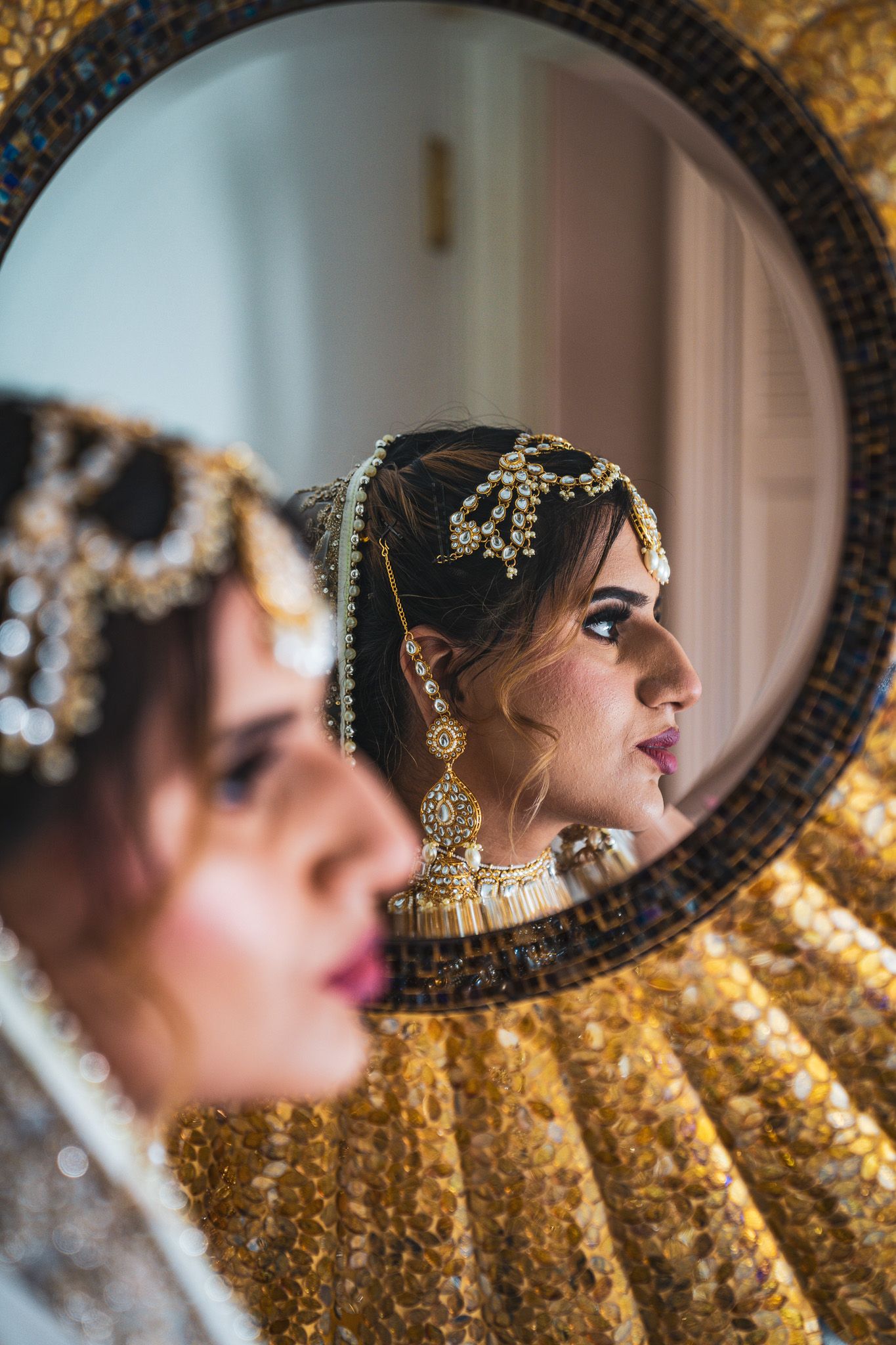Ornate gold mirror reflects elegant bridal jewelry and accessories.