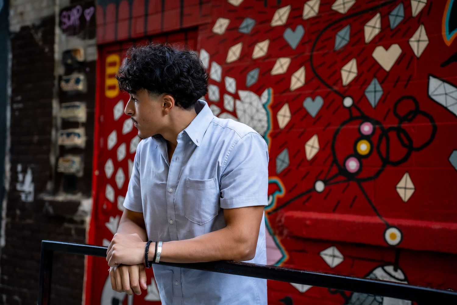 People walking past red wall decorated with white heart patterns.