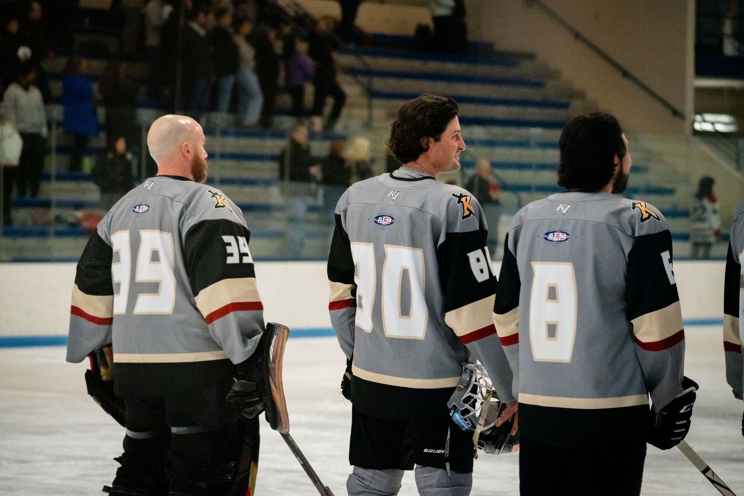 Hockey players in black and white jerseys face off during an ice hockey match.