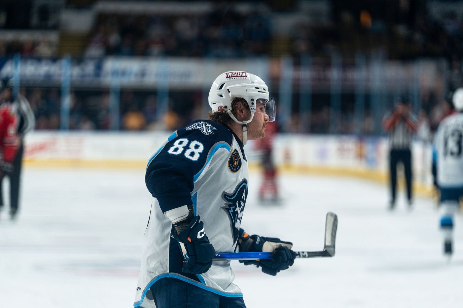 Professional hockey players compete for puck possession during an AHL game on ice.