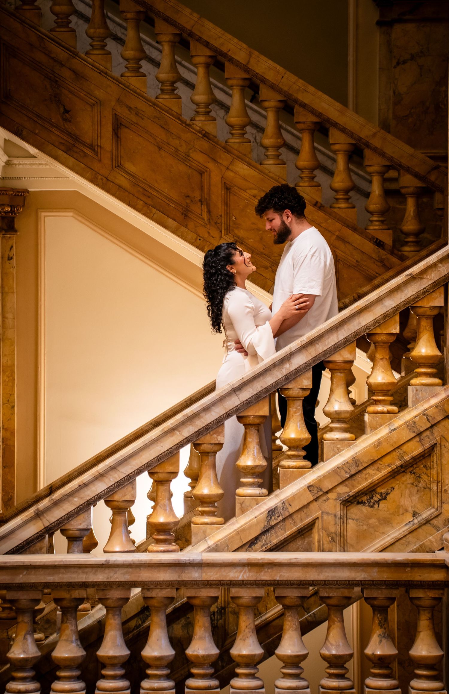 Elegant staircase with ornate wooden banisters in warm lighting creates romantic atmosphere.