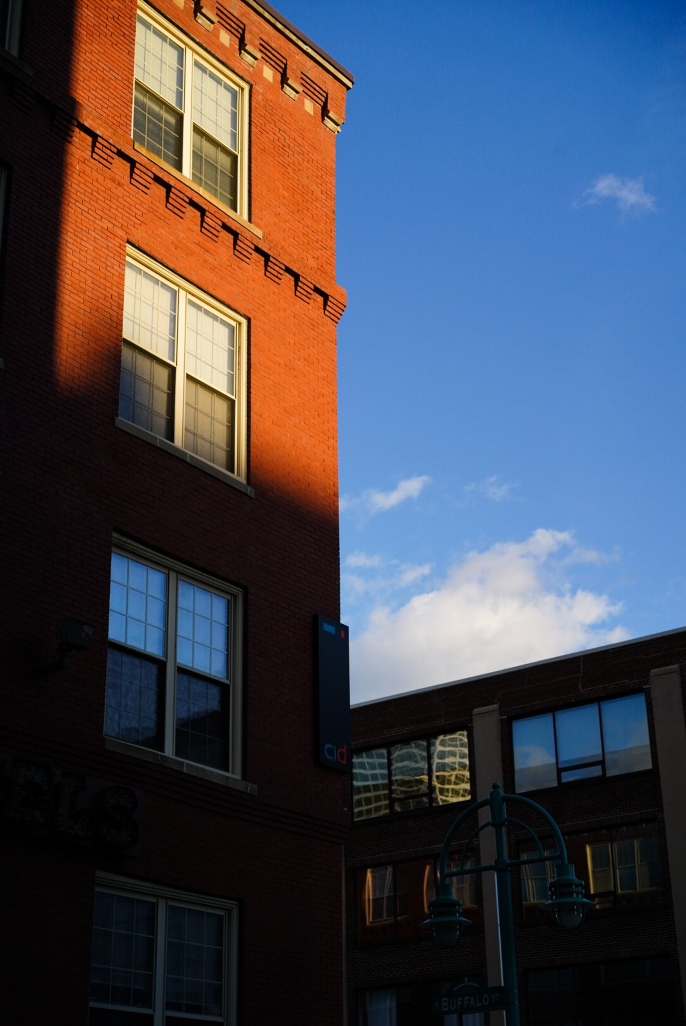 Red brick building facade with windows against bright blue sky.