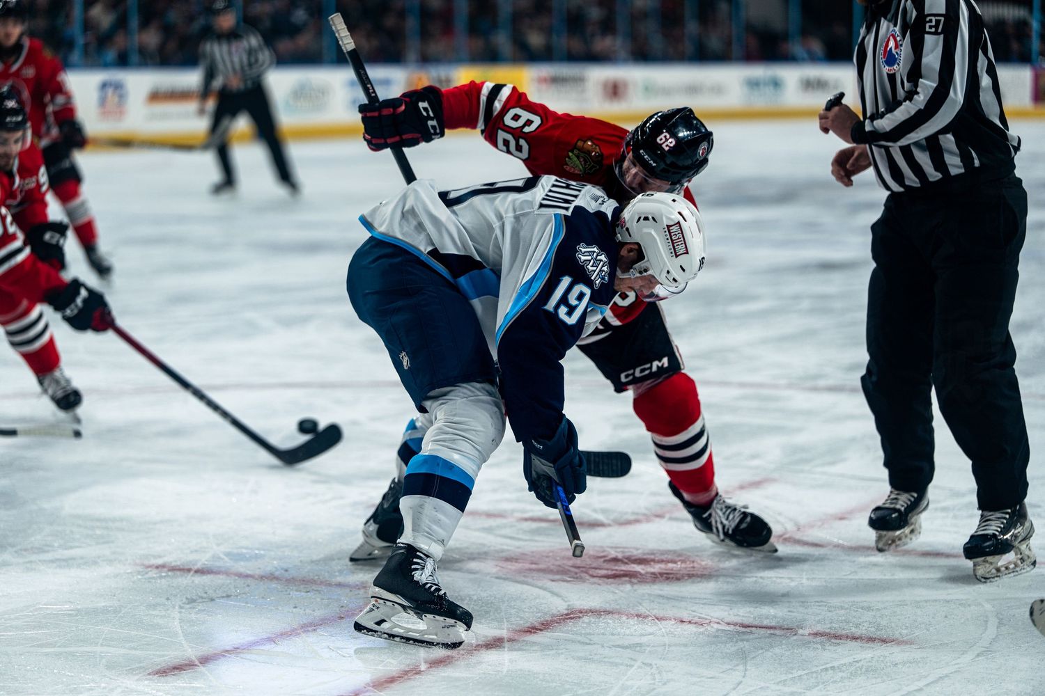 Ice hockey players battle for puck control during competitive match on the rink.