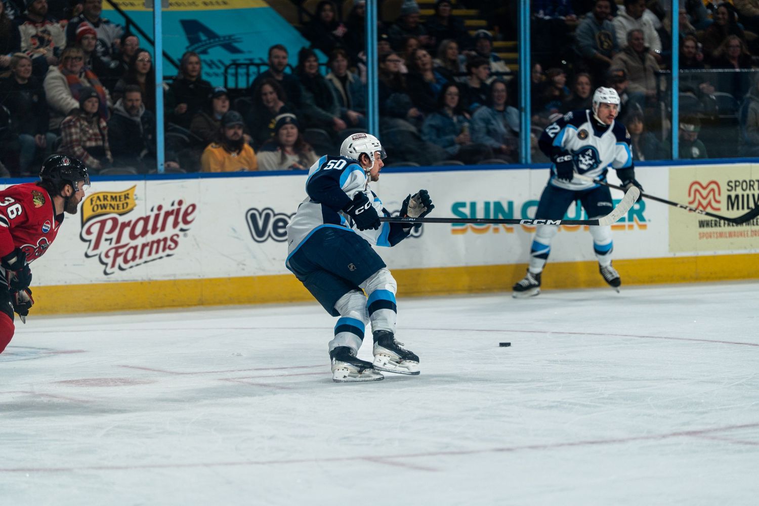 Hockey players compete for the puck during an intense game on the ice.