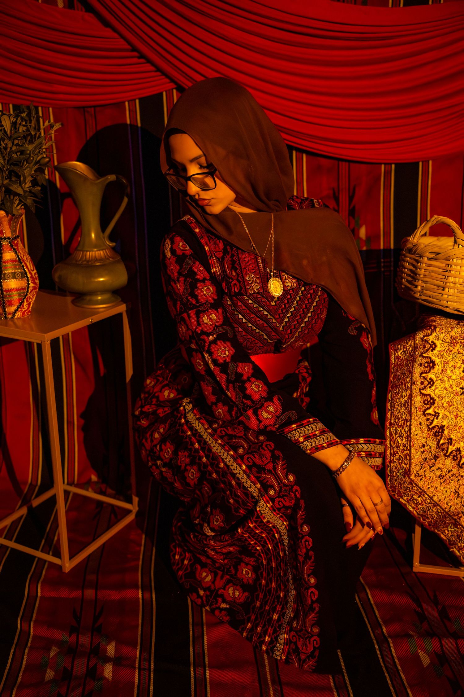 A series of red-tinted photos showing a person in ornate dark clothing against dramatic red drapery in a vintage setting.