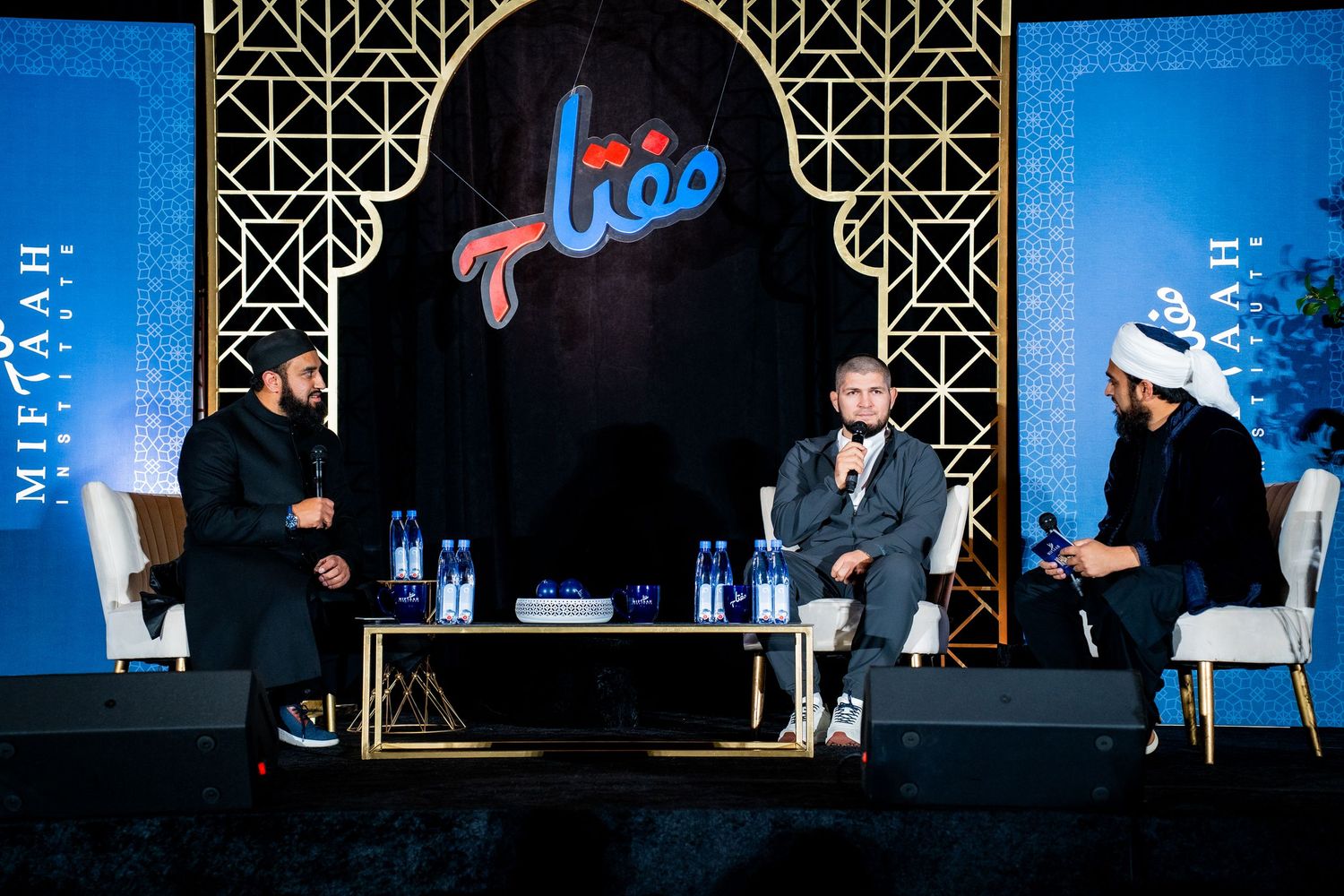 Panel discussion taking place on stage with speakers seated at a table during a business conference event.