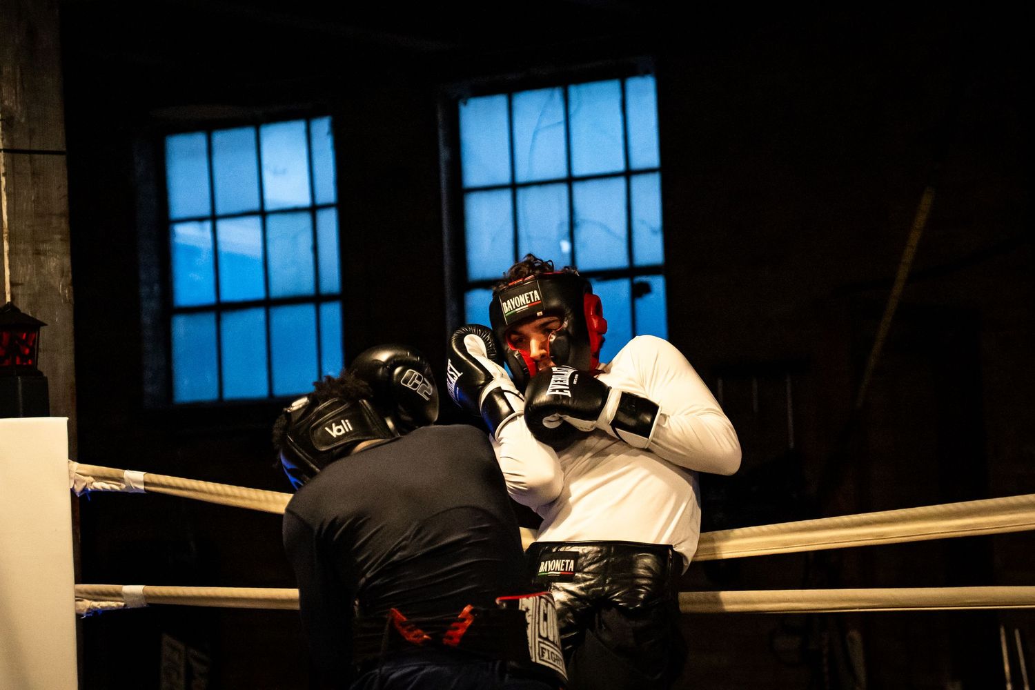 Boxing match in progress with fighters wearing protective equipment in a classic gym setting.