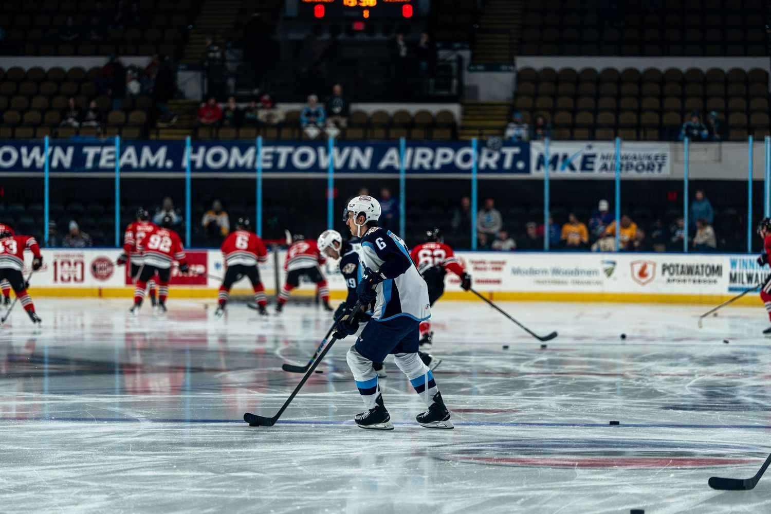 Hockey players compete on ice during a professional game with arena signage visible in the background.