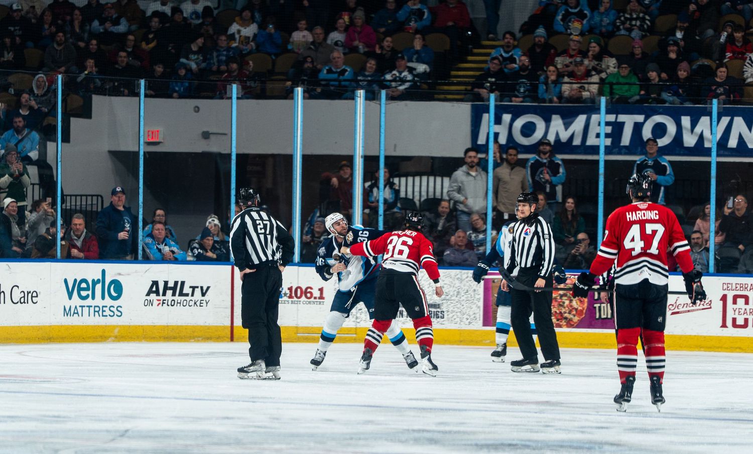 Hockey players compete on ice during a professional game with spectators in the background.