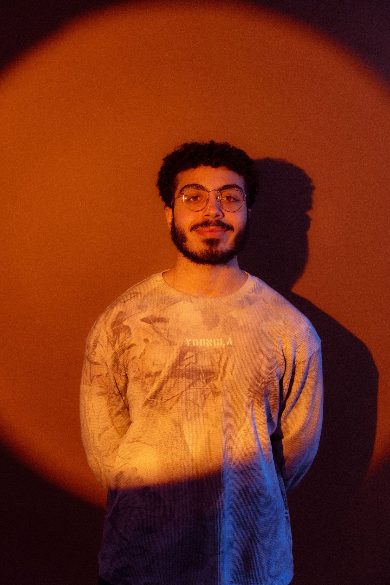 A portrait photo with dramatic orange and blue lighting creates a moody atmosphere against a dark background.