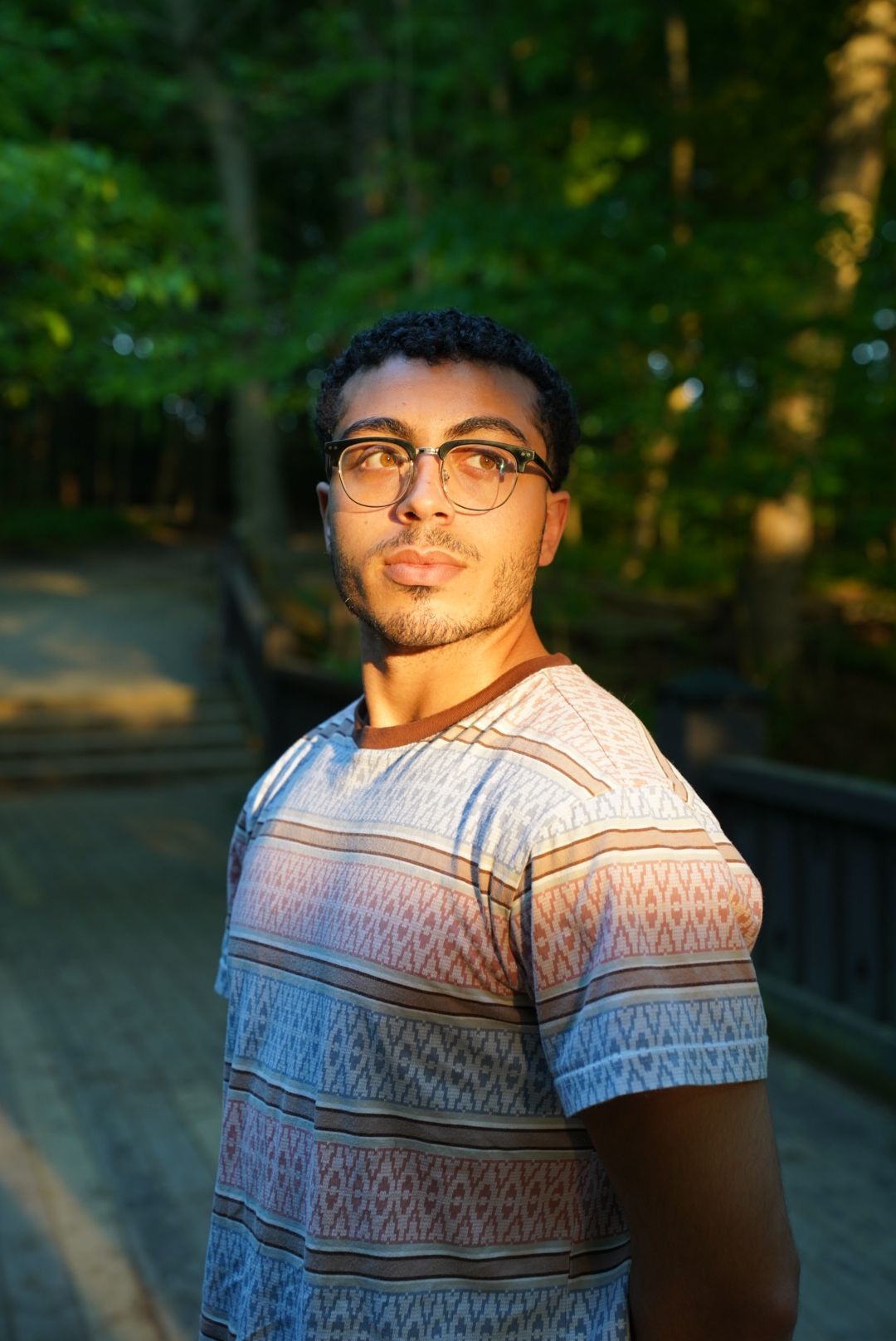 Portrait in natural lighting with trees and sunset in background.