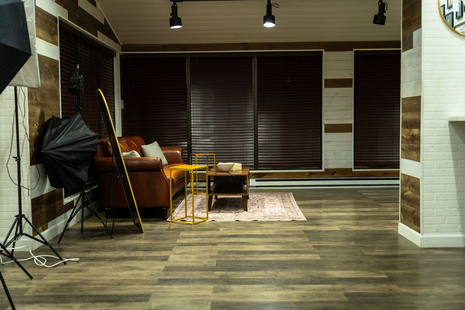 Modern fitness studio interior with wooden flooring, track lighting, and mirrored walls ready for exercise classes.