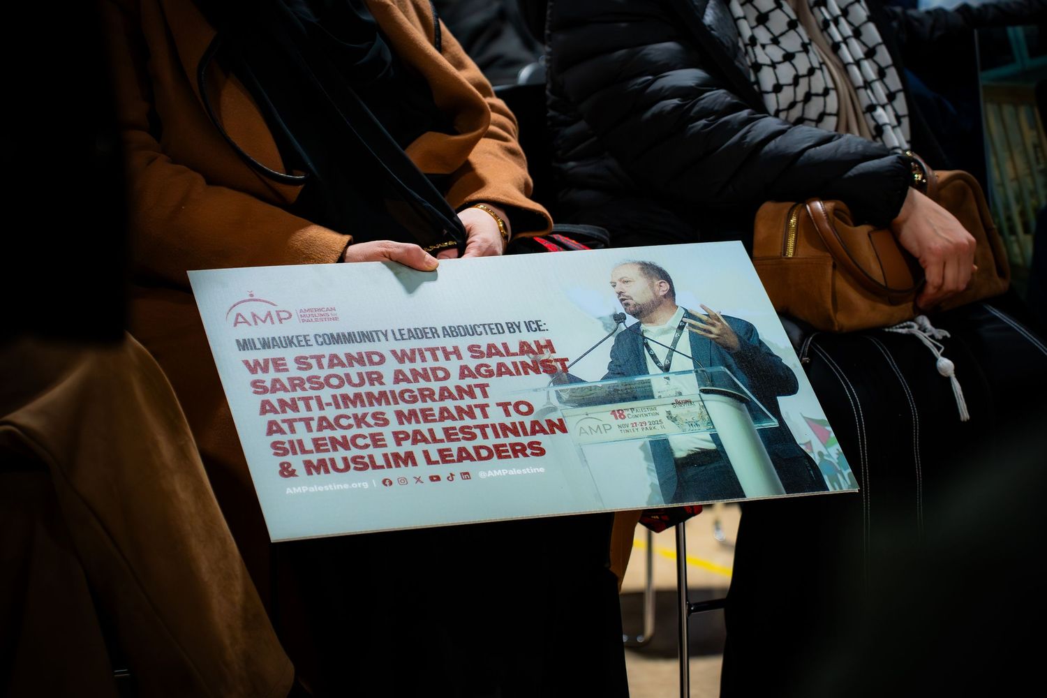 Person holding a sign expressing solidarity with Salah Sarsour against anti-immigrant attacks at a community gathering.