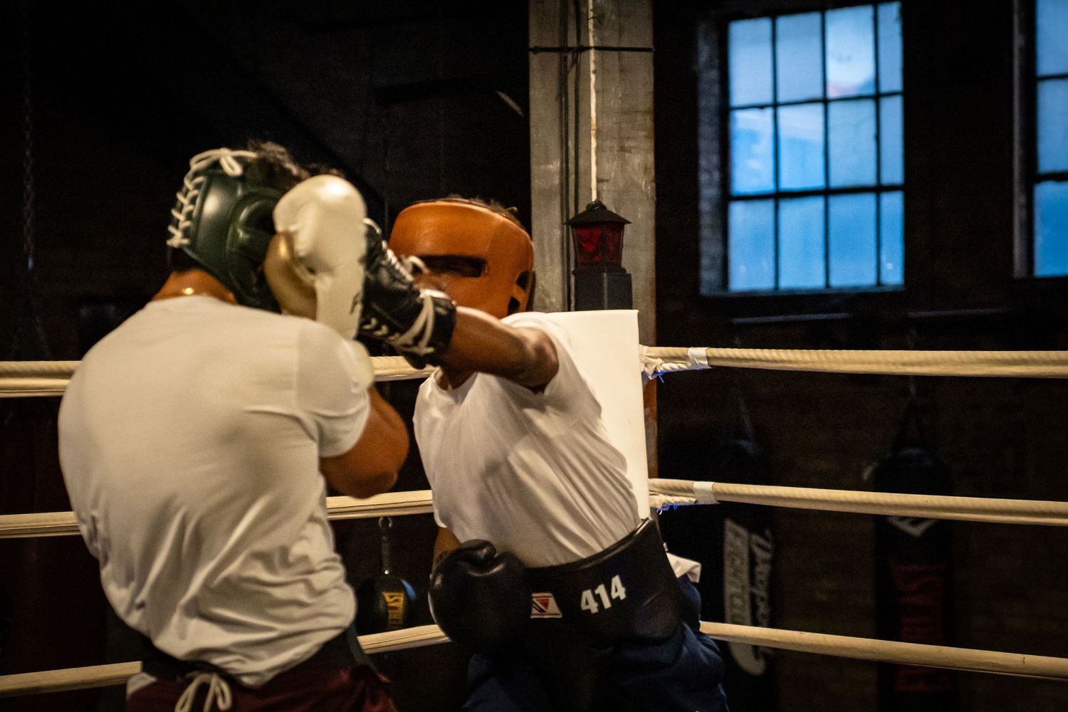 Boxers exchange punches during an intense sparring session in a boxing gym.