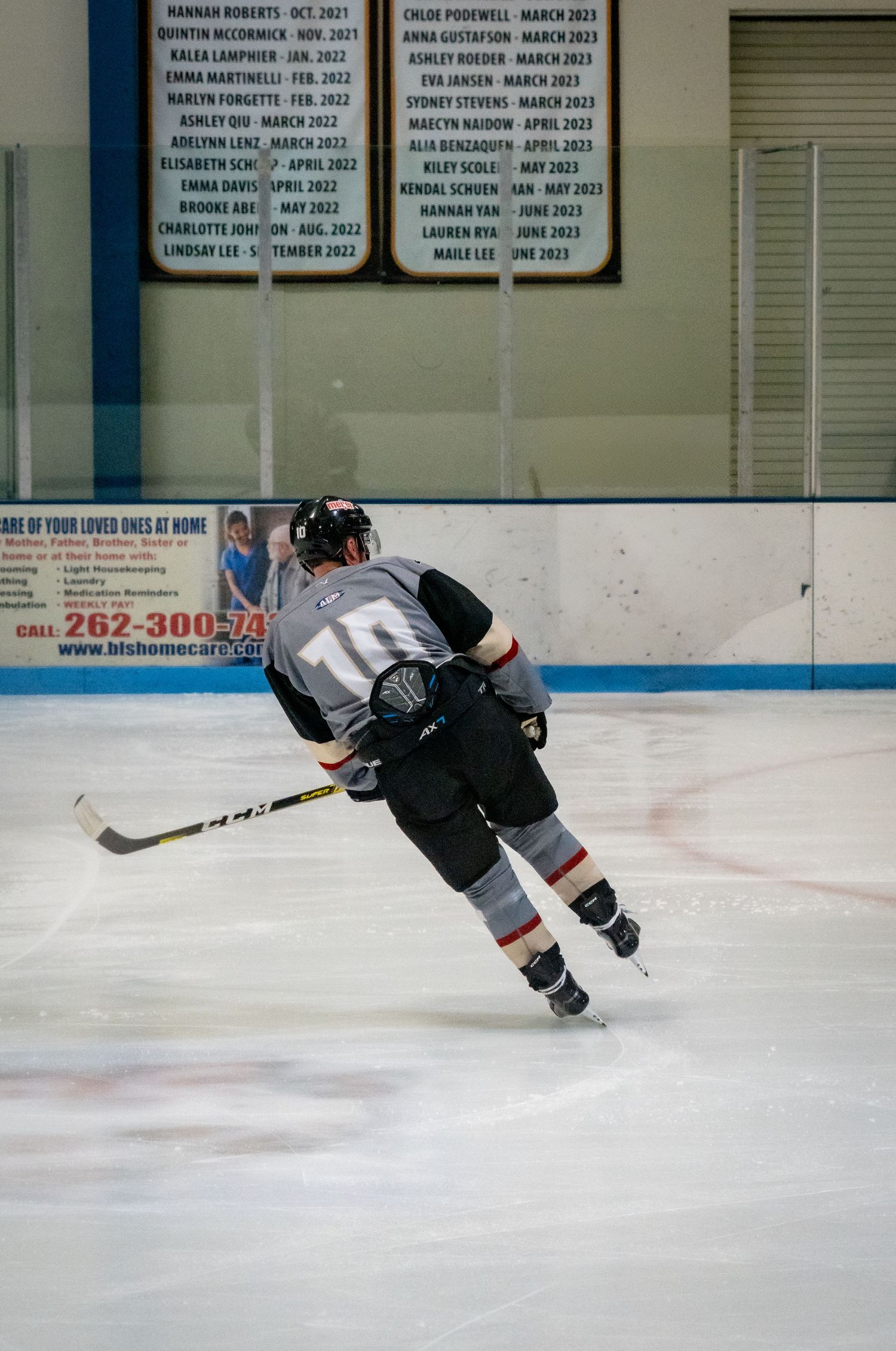 Hockey player in black jersey performs skating drill on ice rink during practice session.