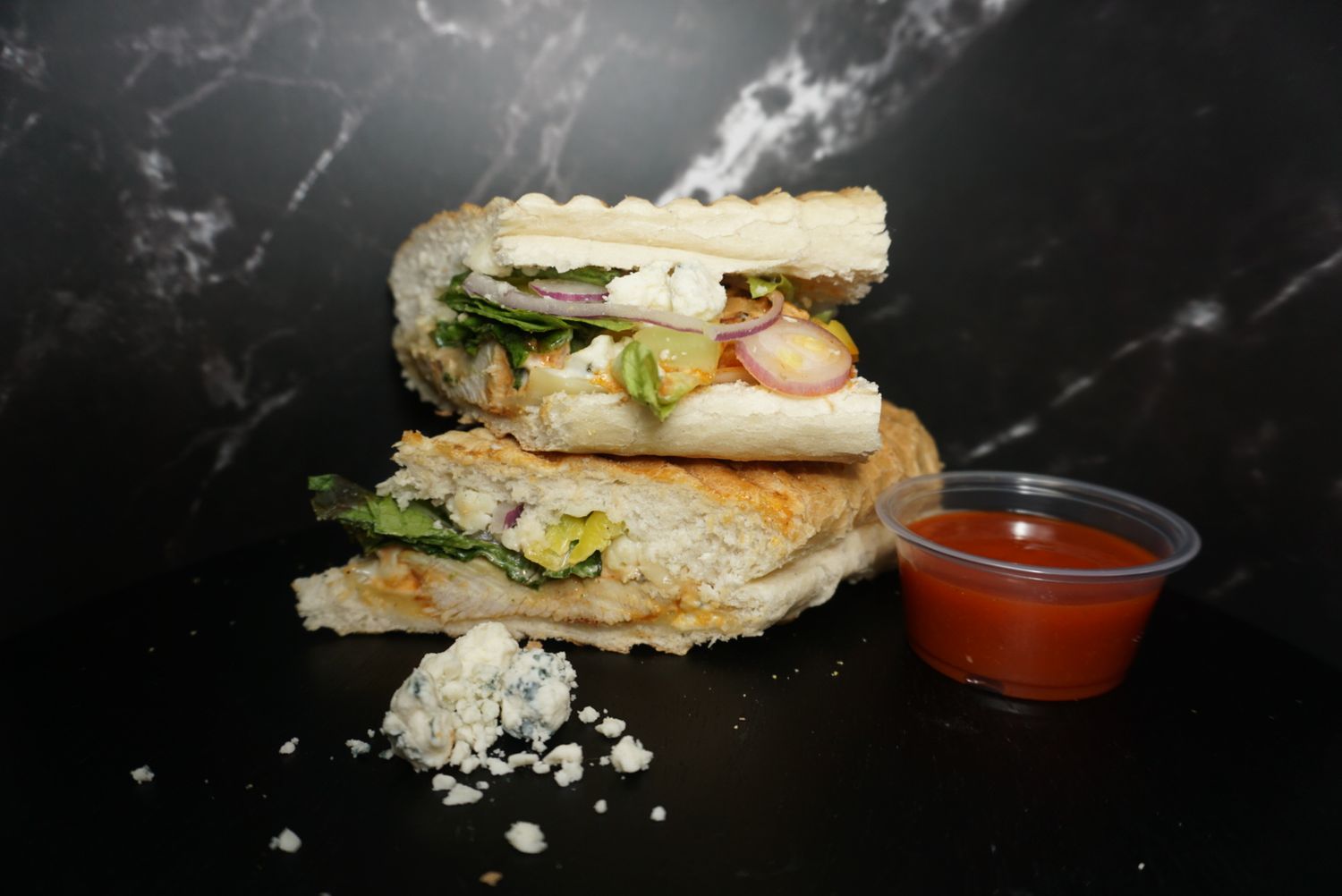 Club sandwich cut diagonally with tomatoes and lettuce served with dipping sauce.