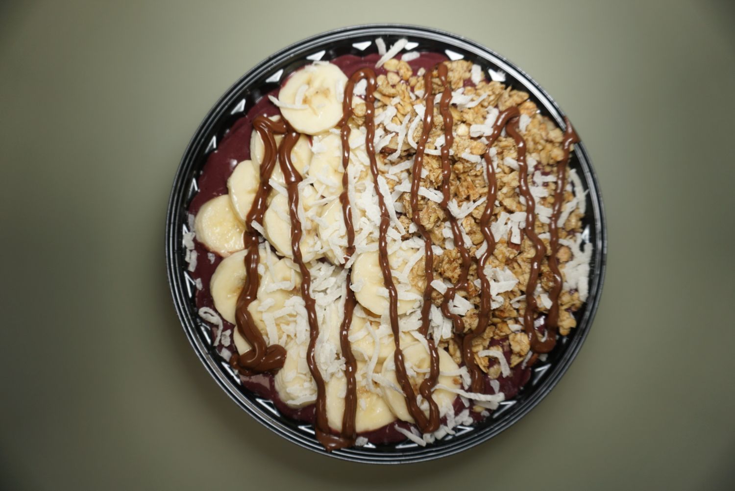 Chocolate drizzled dessert bowl with sliced bananas and whipped cream.
