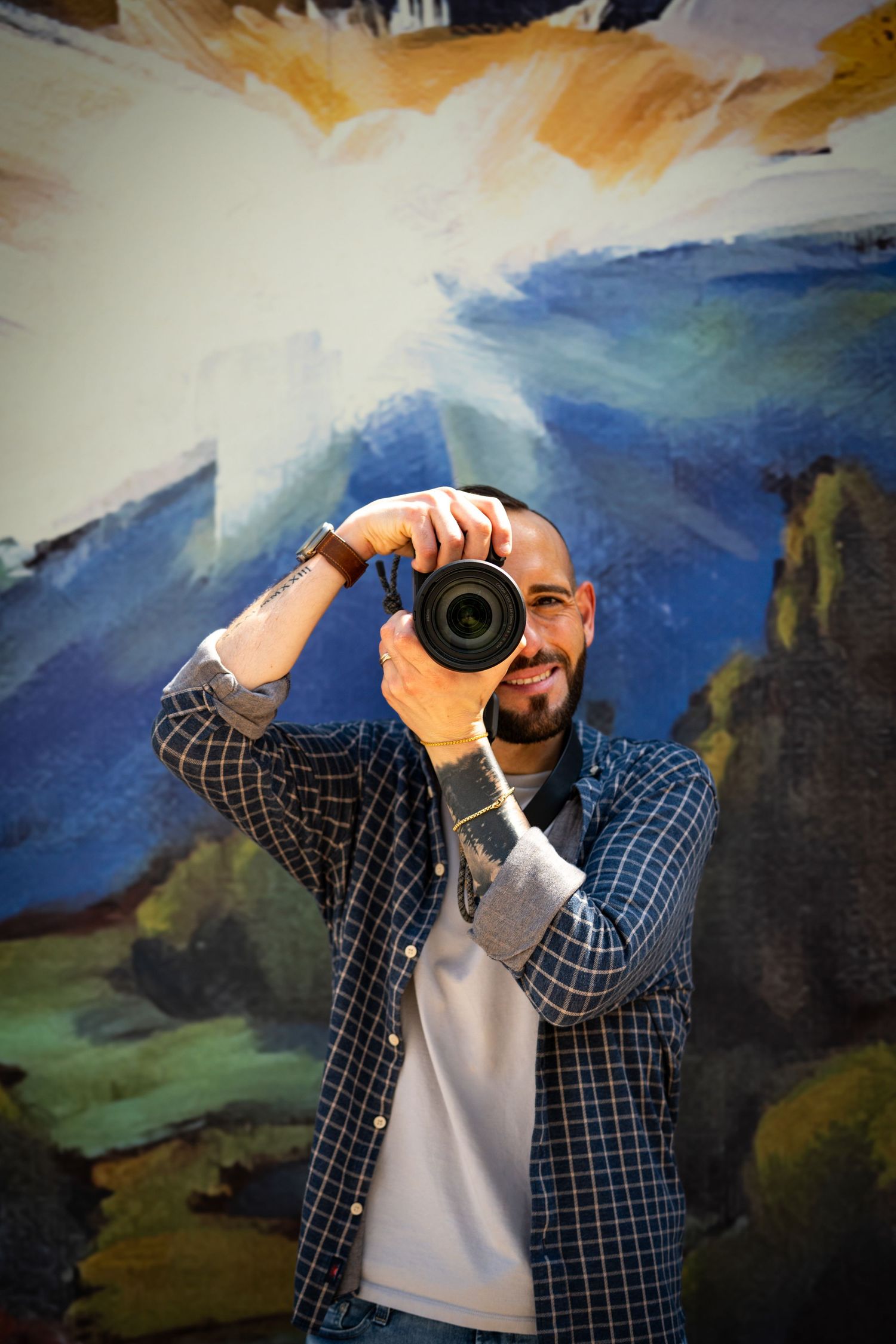 Photographer with camera against colorful painted wall background.
