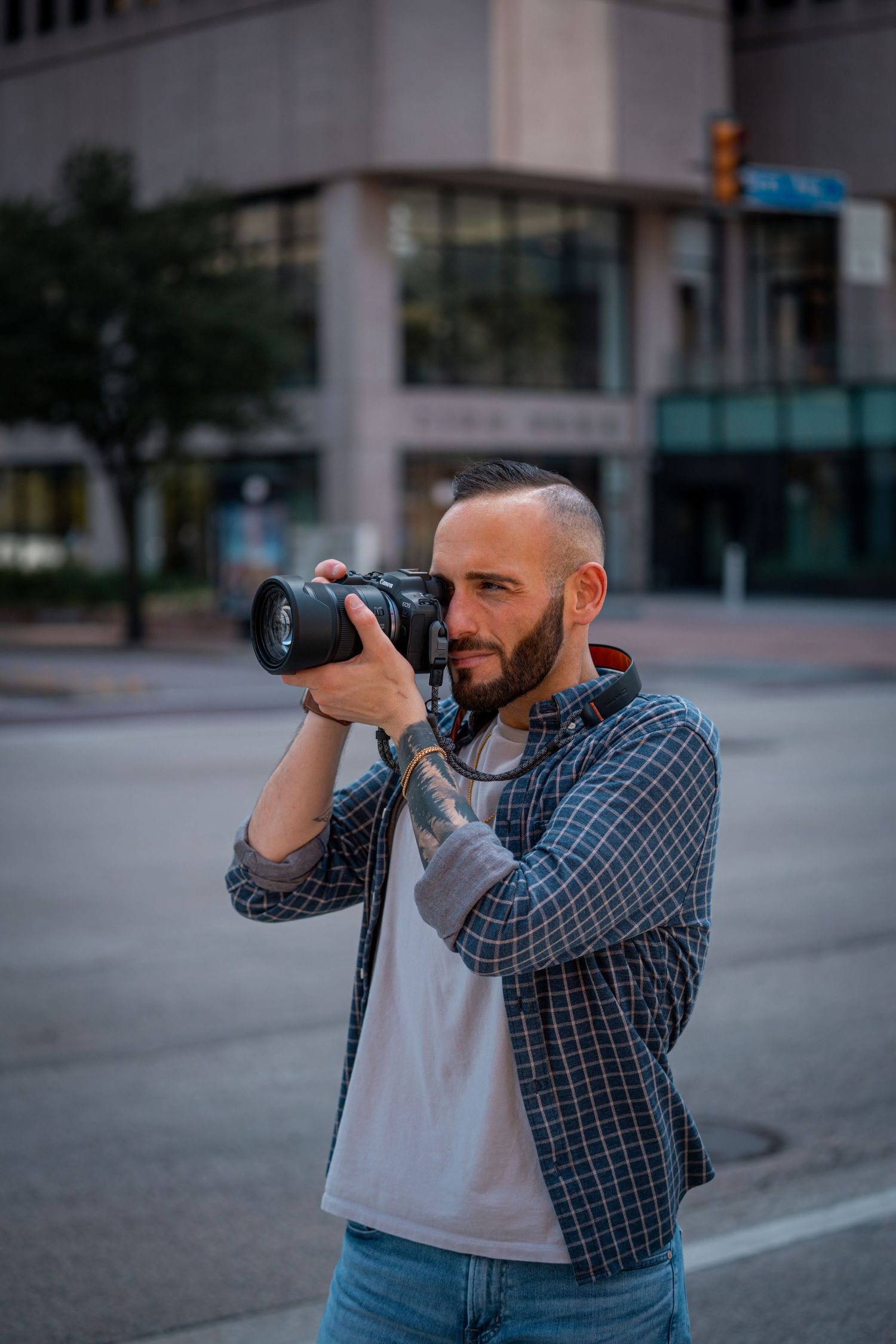 Photographer in plaid shirt taking photos with professional camera in urban setting.