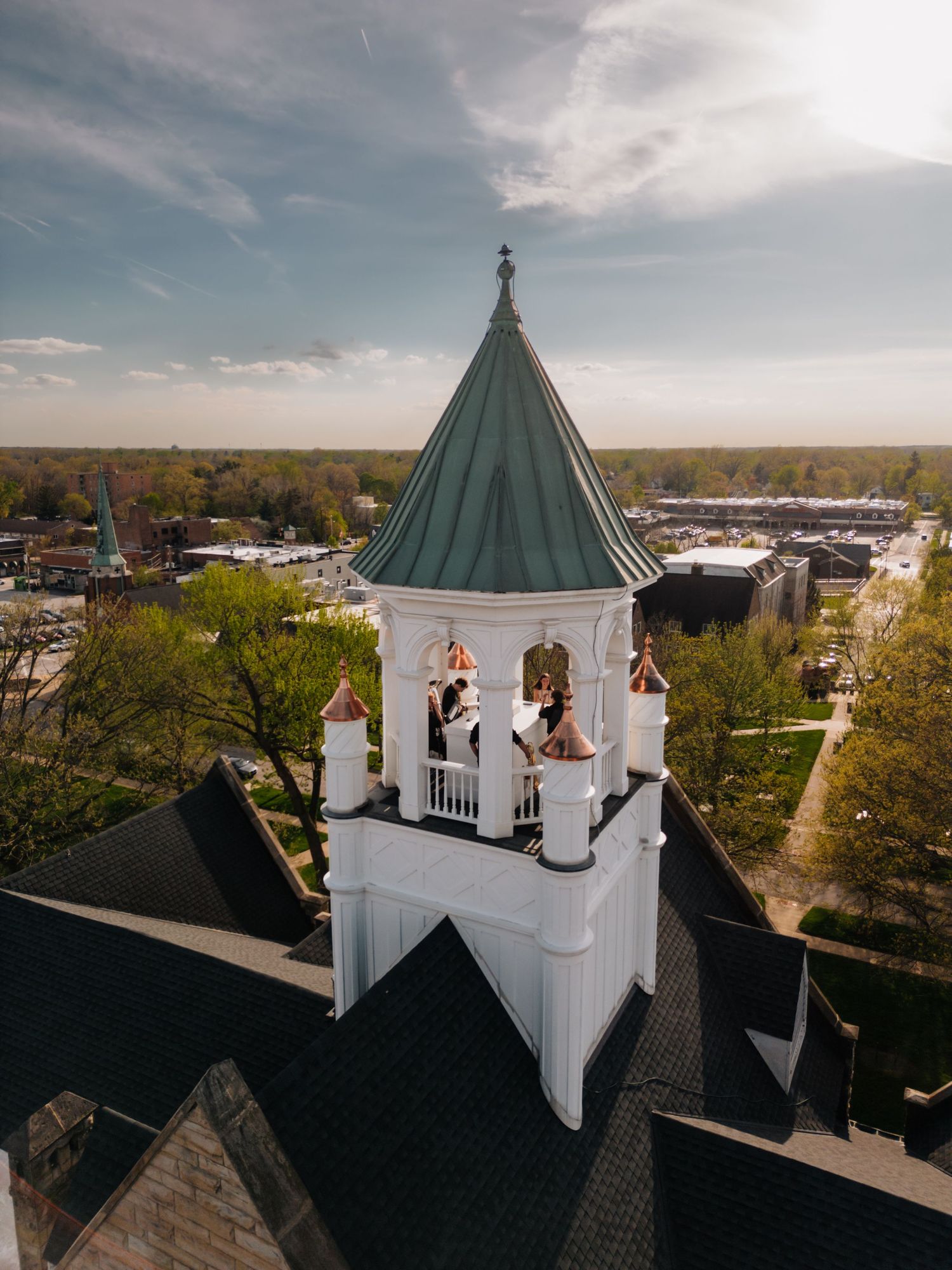 Aerial drone view of a wedding couple in a white church bell tower at sunset.