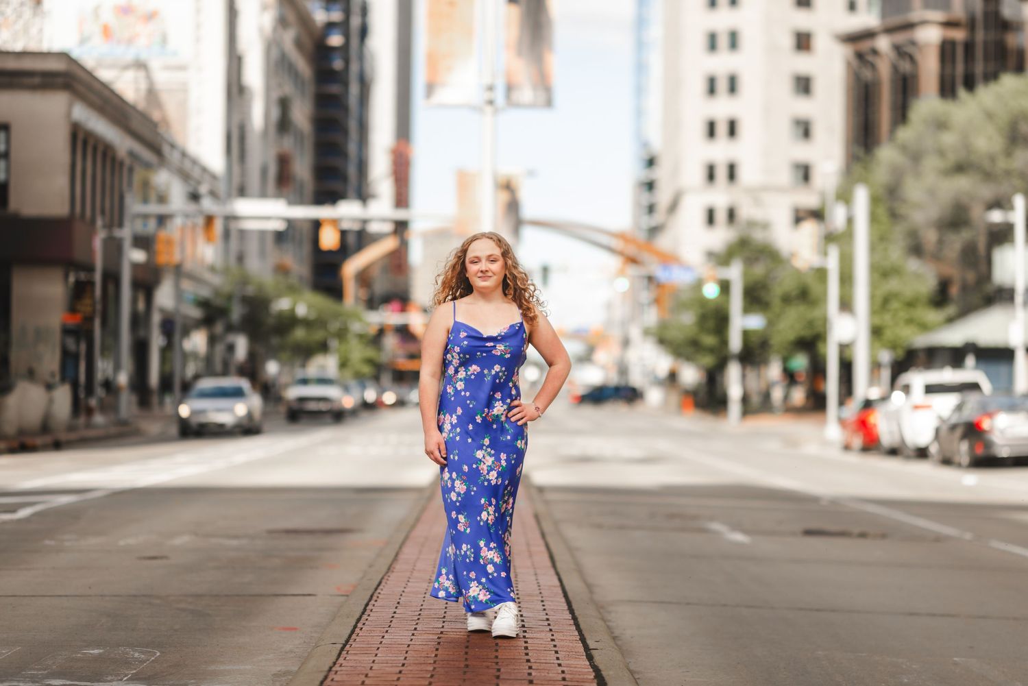 Woman in blue floral maxi dress standing confidently in the middle of an urban city street.