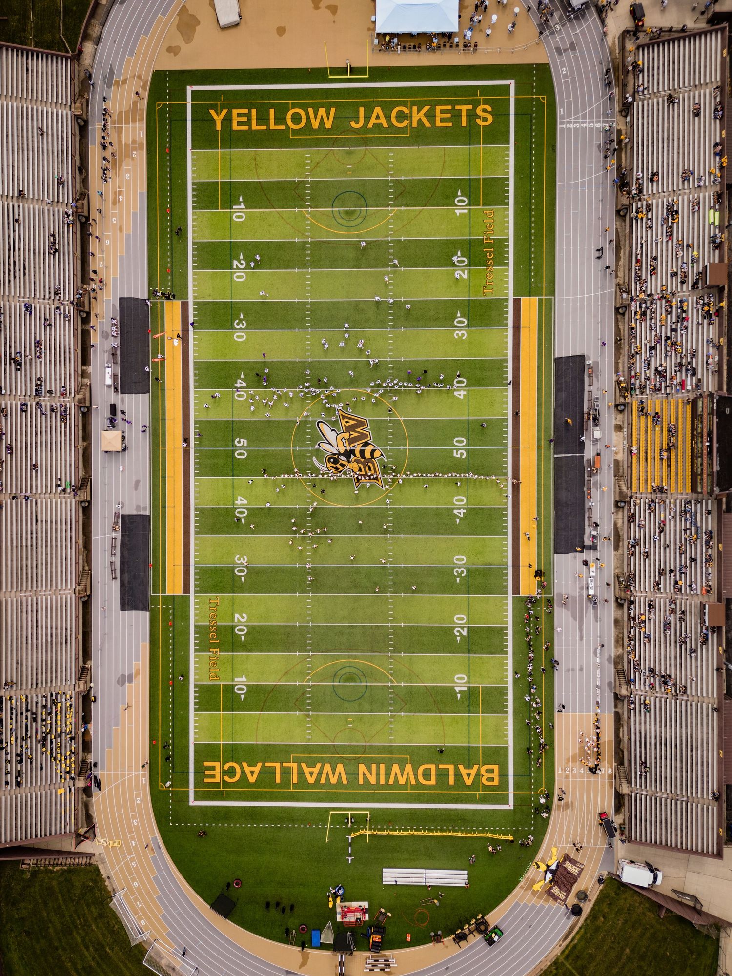 Aerial view of Baldwin Wallace Yellow Jackets football field with players on the green turf stadium.