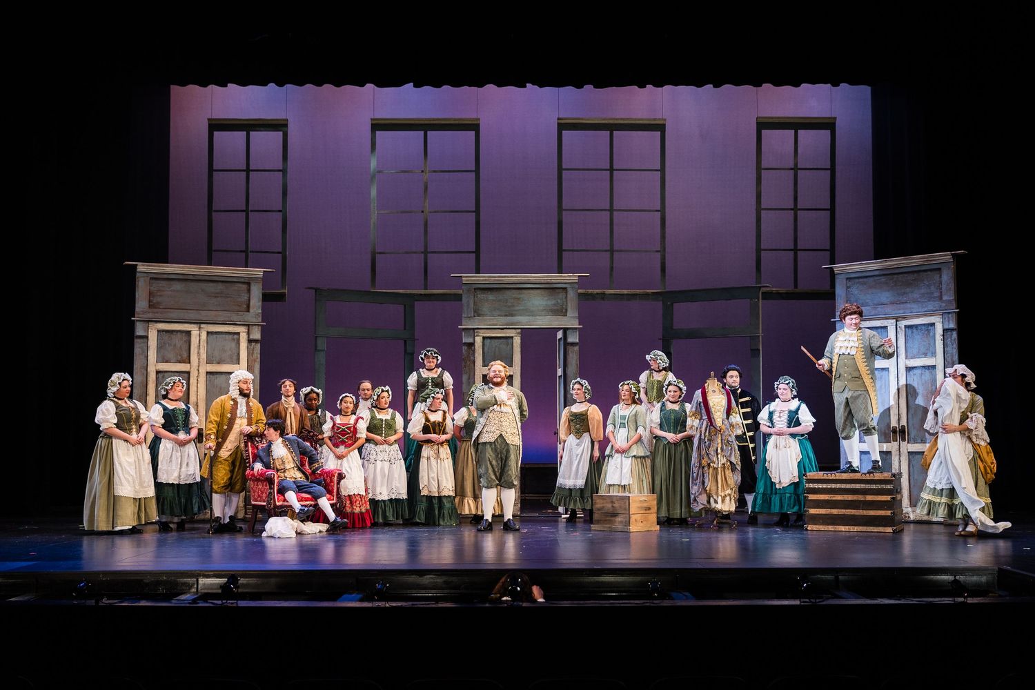 Full cast ensemble on stage in period costumes during a theatrical opera production.