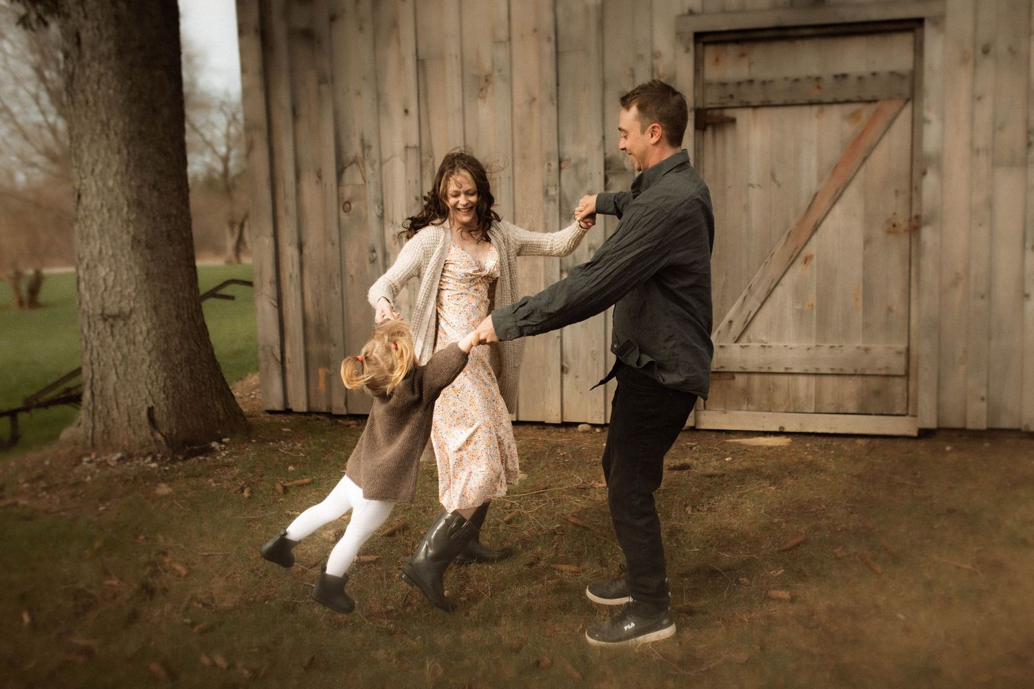 A family playing outside in the spring sunshine during an at-home family photography session by Oshawa Family Photographer.