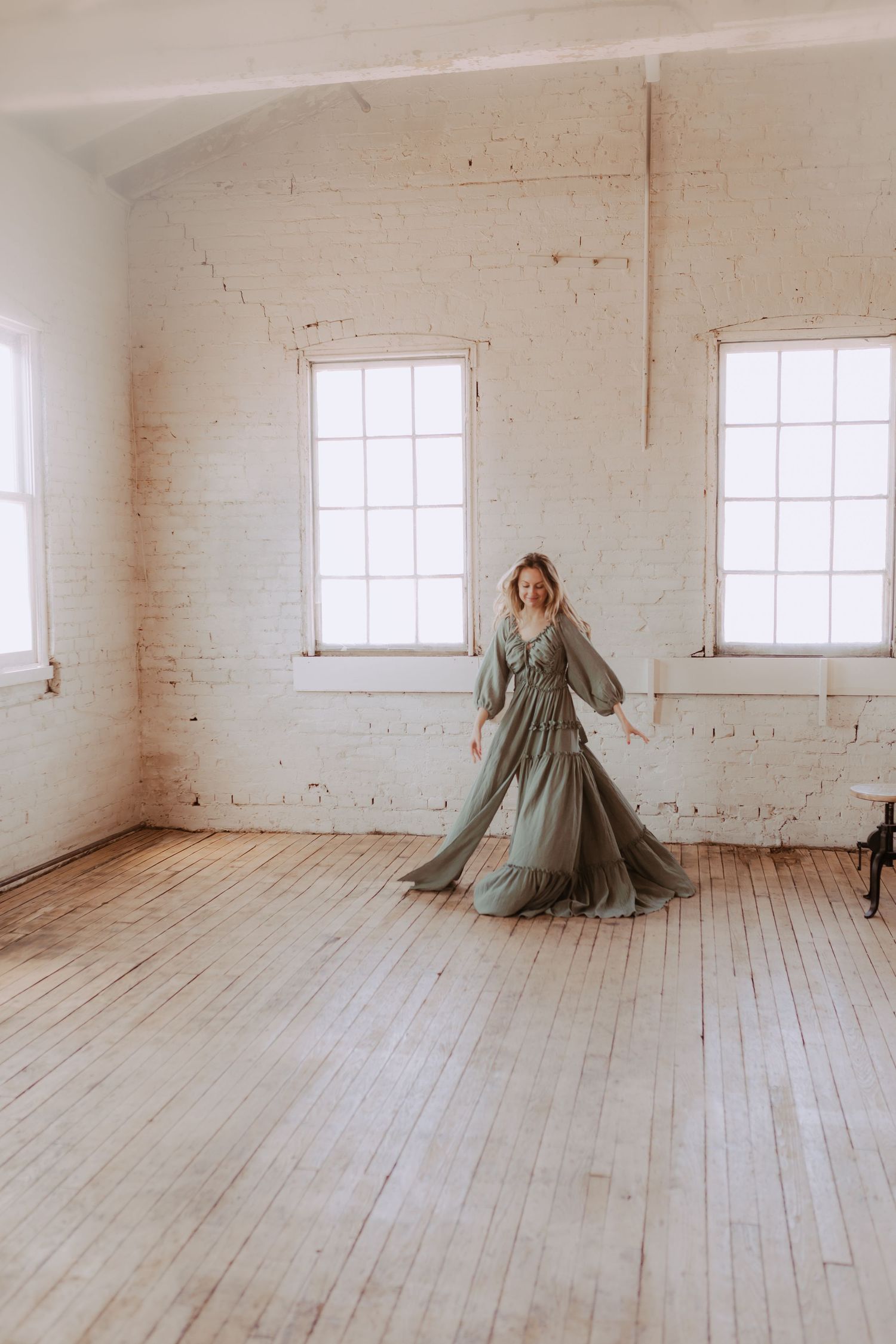 Artistic portrait in a bright white studio with wooden floors and natural window light.