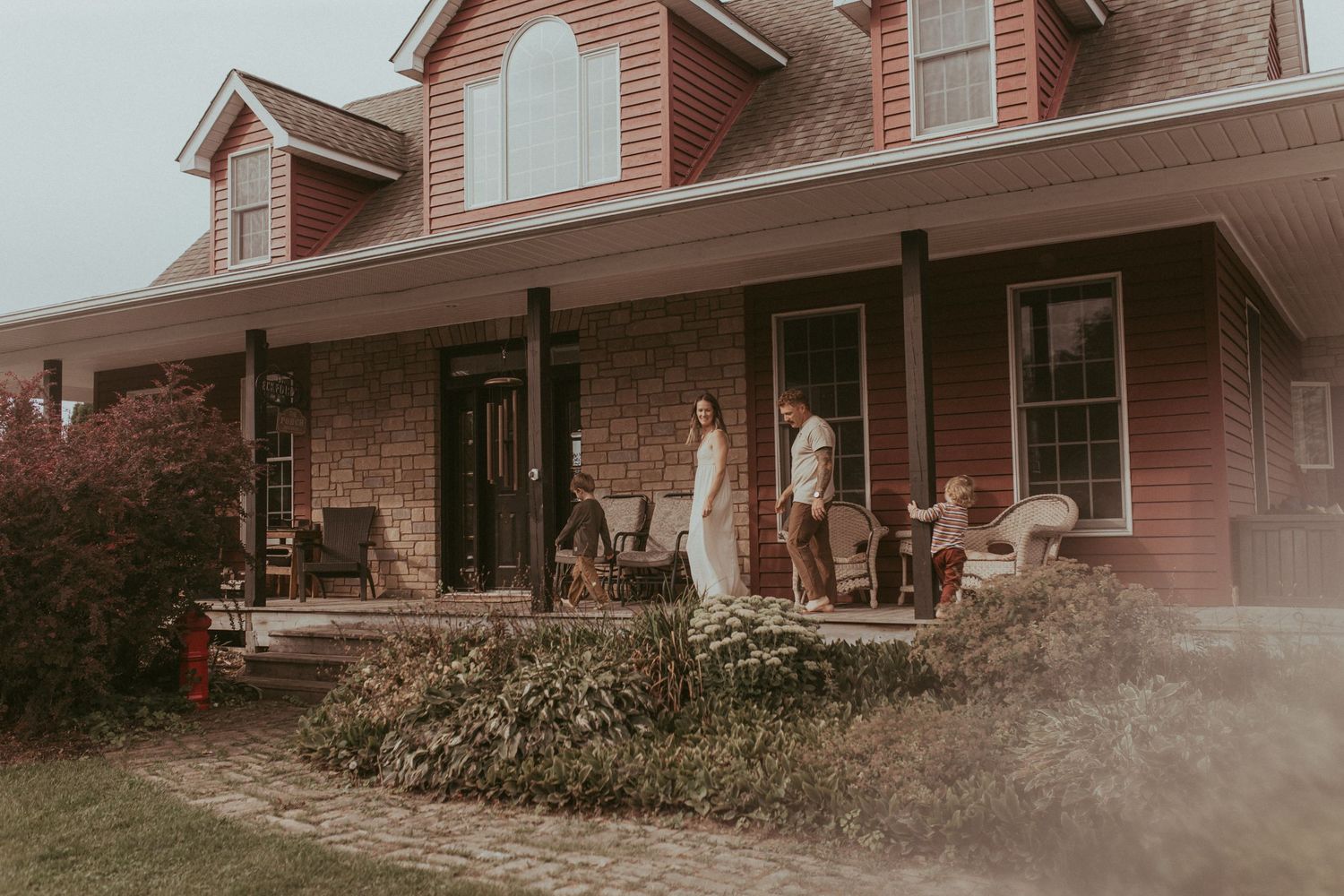 The family is walking towards their front door on their porch at the end of a Durham Region family lifestyle photography shoot.
