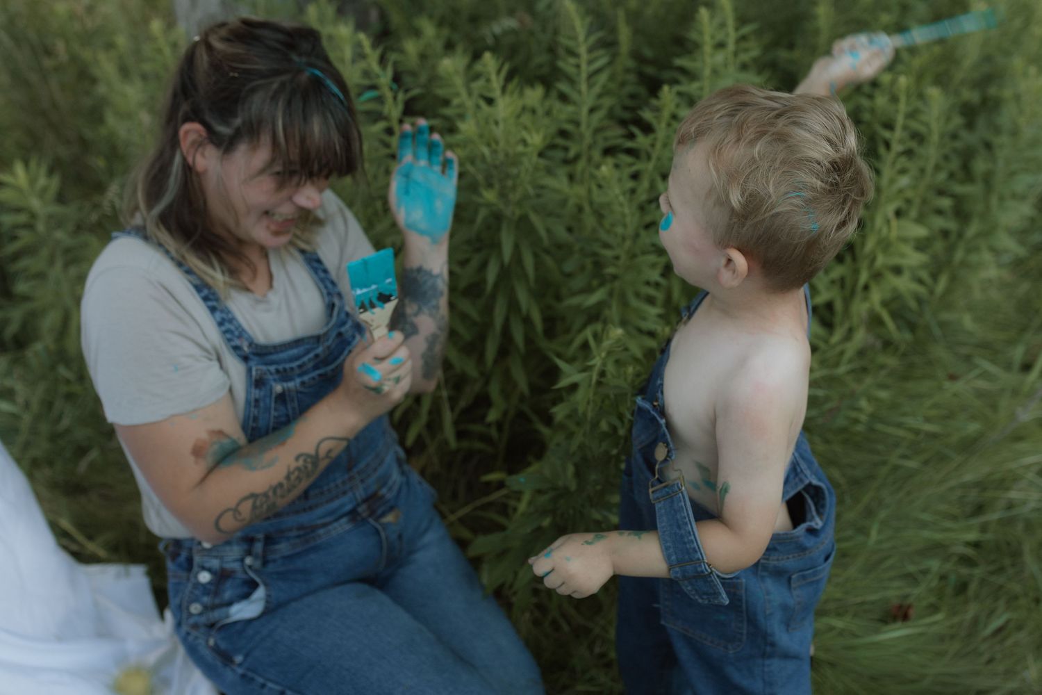 A mom and son splash paint on each other during a painting session by Courtice family photographer